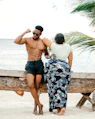 A man and a woman sitting on a bench at the beach