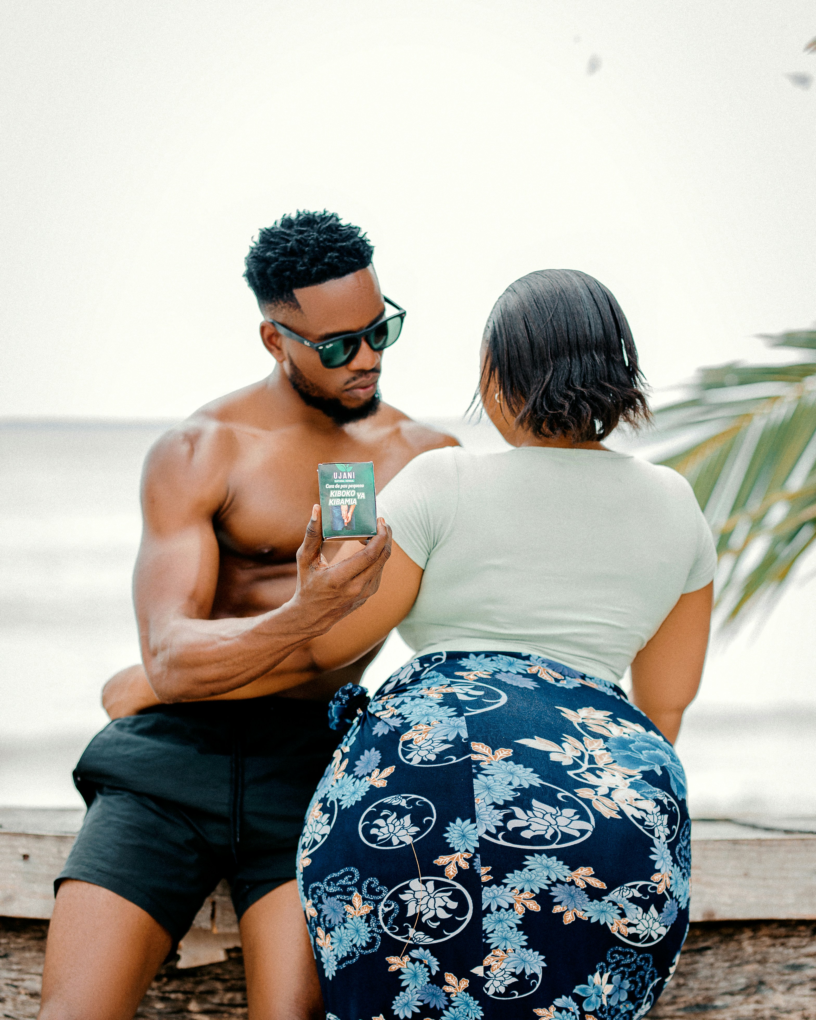 A man and a woman sitting on a wall looking at a cell phone
