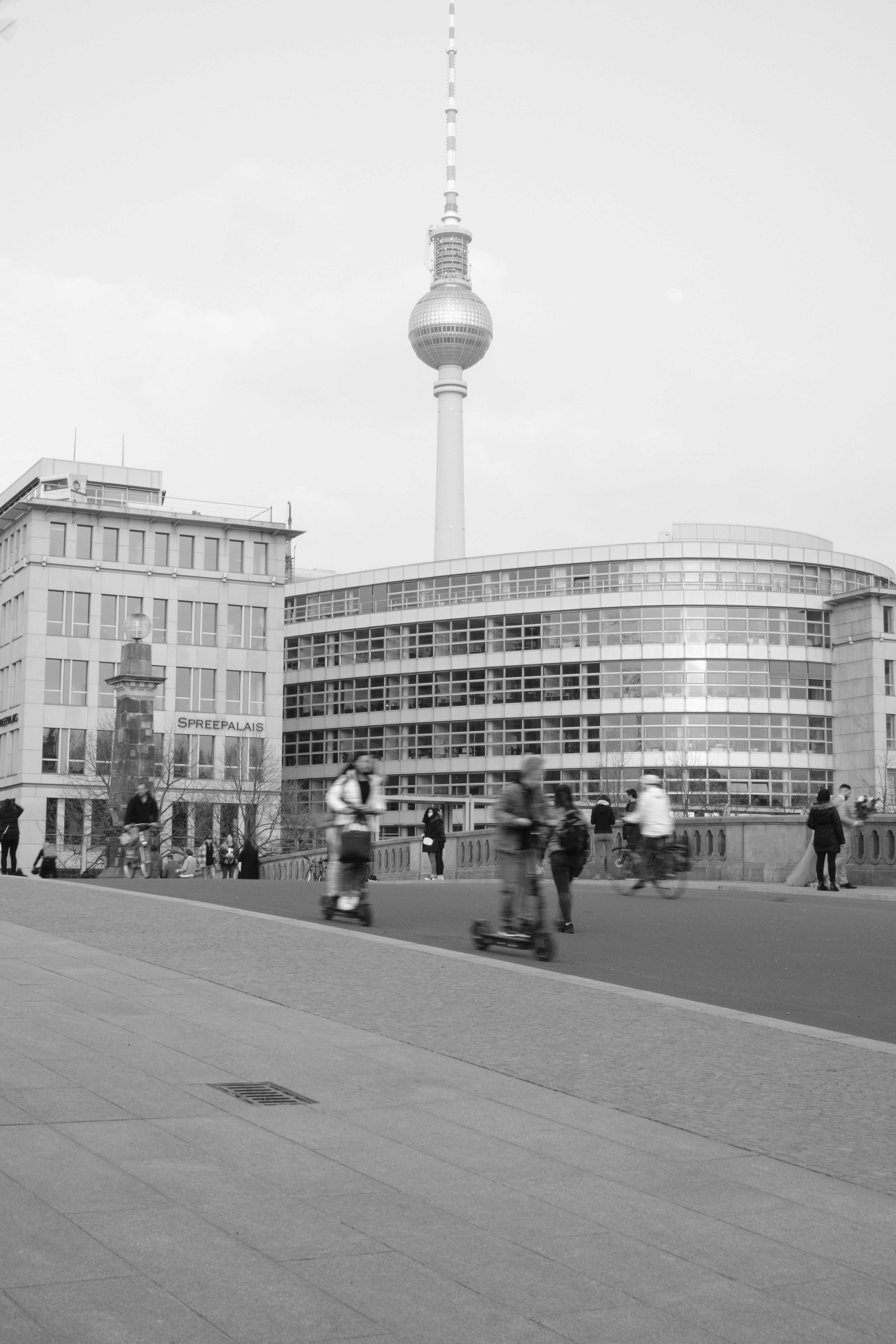 A black and white photo of people walking on a sidewalk