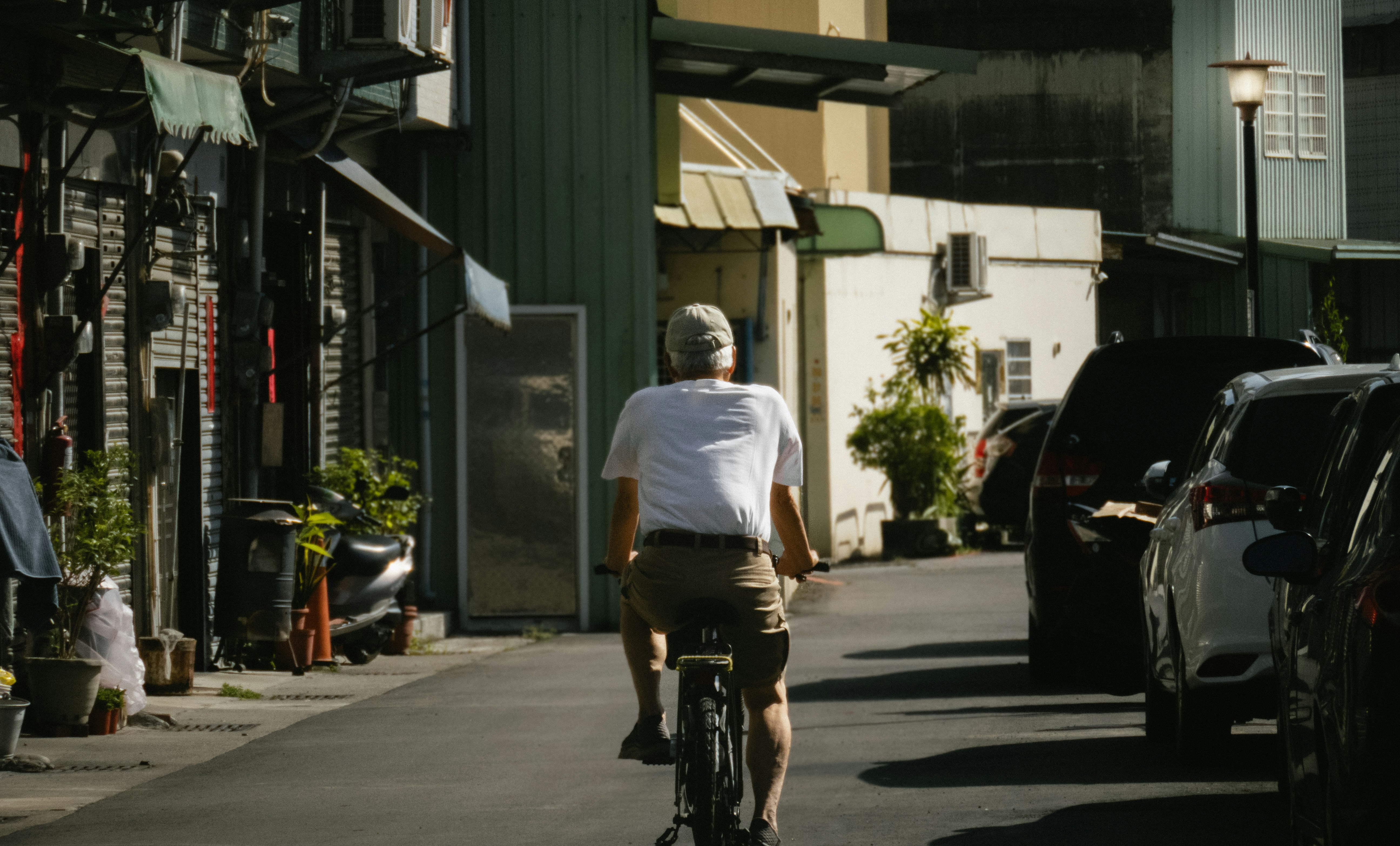 A man riding a bike down a street next to parked cars