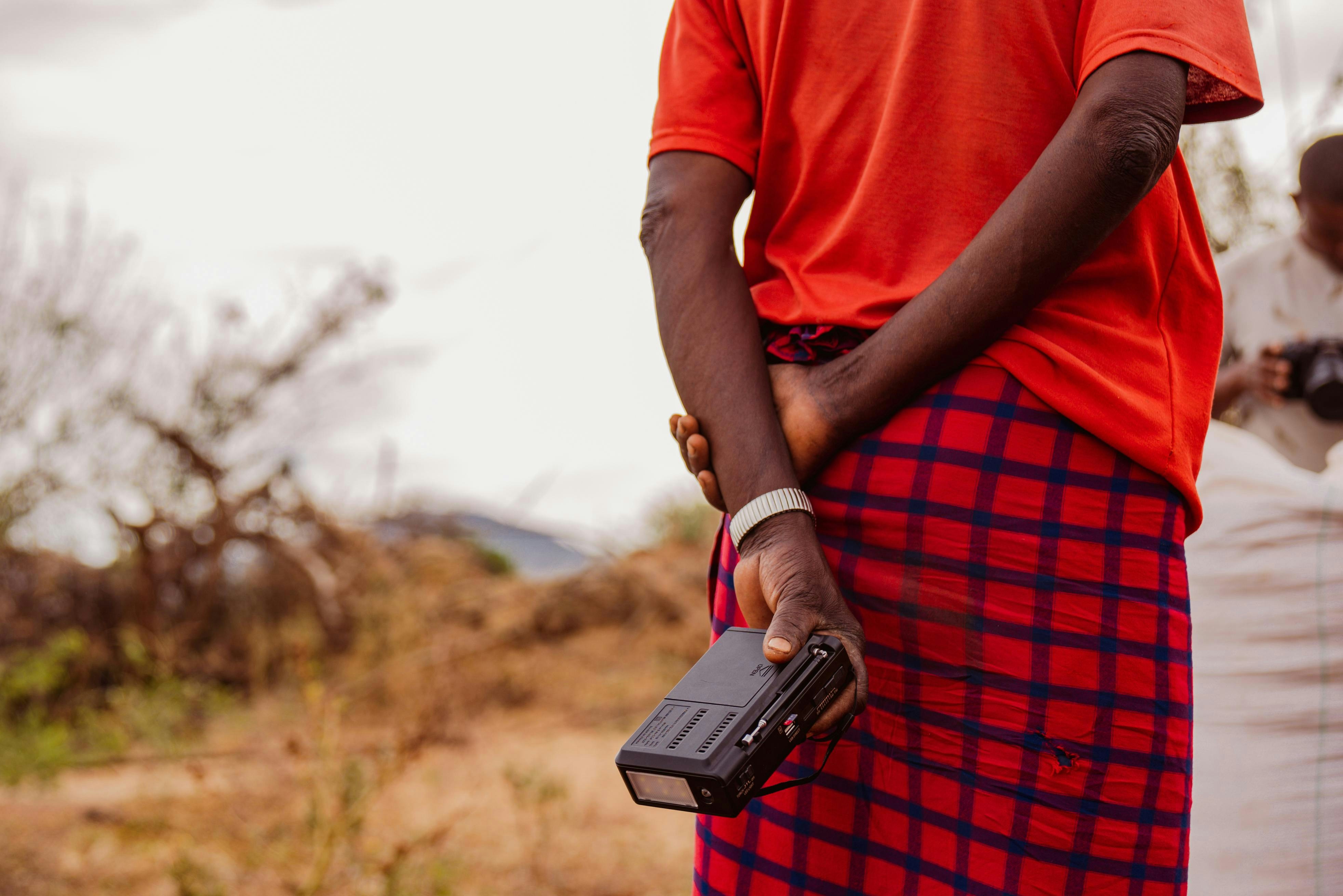 A man in a red shirt is holding a cell phone