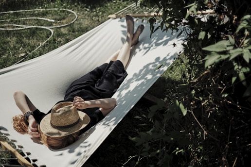 A man laying in a hammock with a hat on