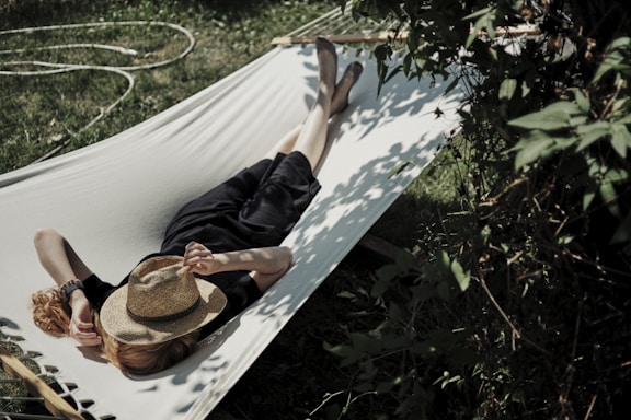 A man laying in a hammock with a hat on