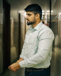 A man in a white shirt leaning against a wall