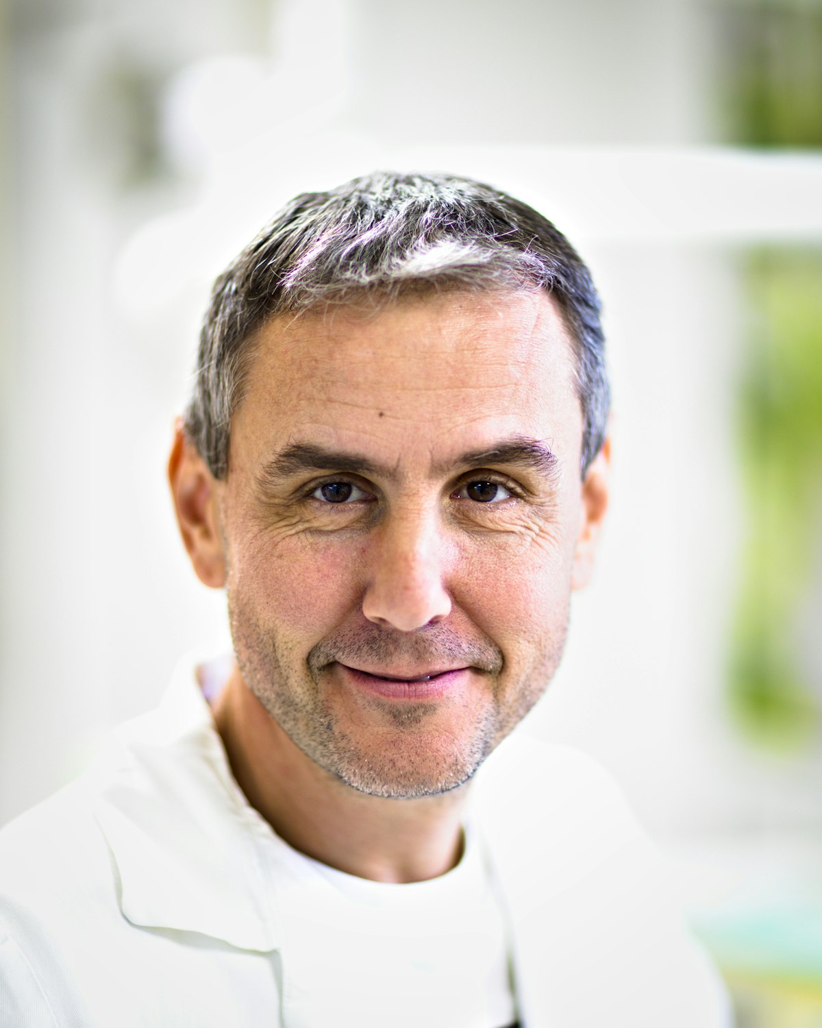Smiling male dentist in a white lab coat, founder of Bayview Smile Center