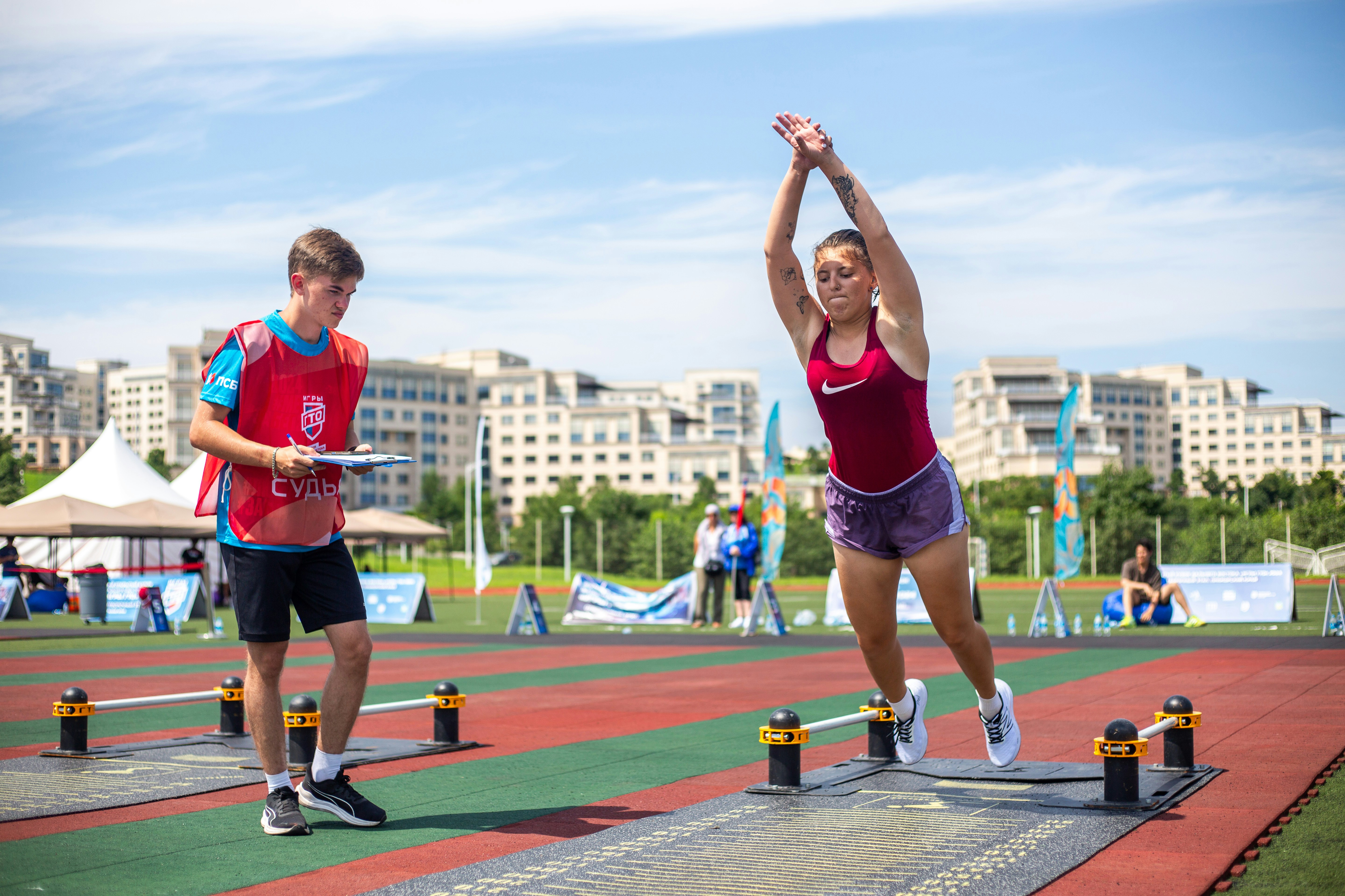 A man and a woman are jumping over obstacles