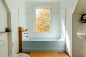 A bathroom with a tub, sink, and window