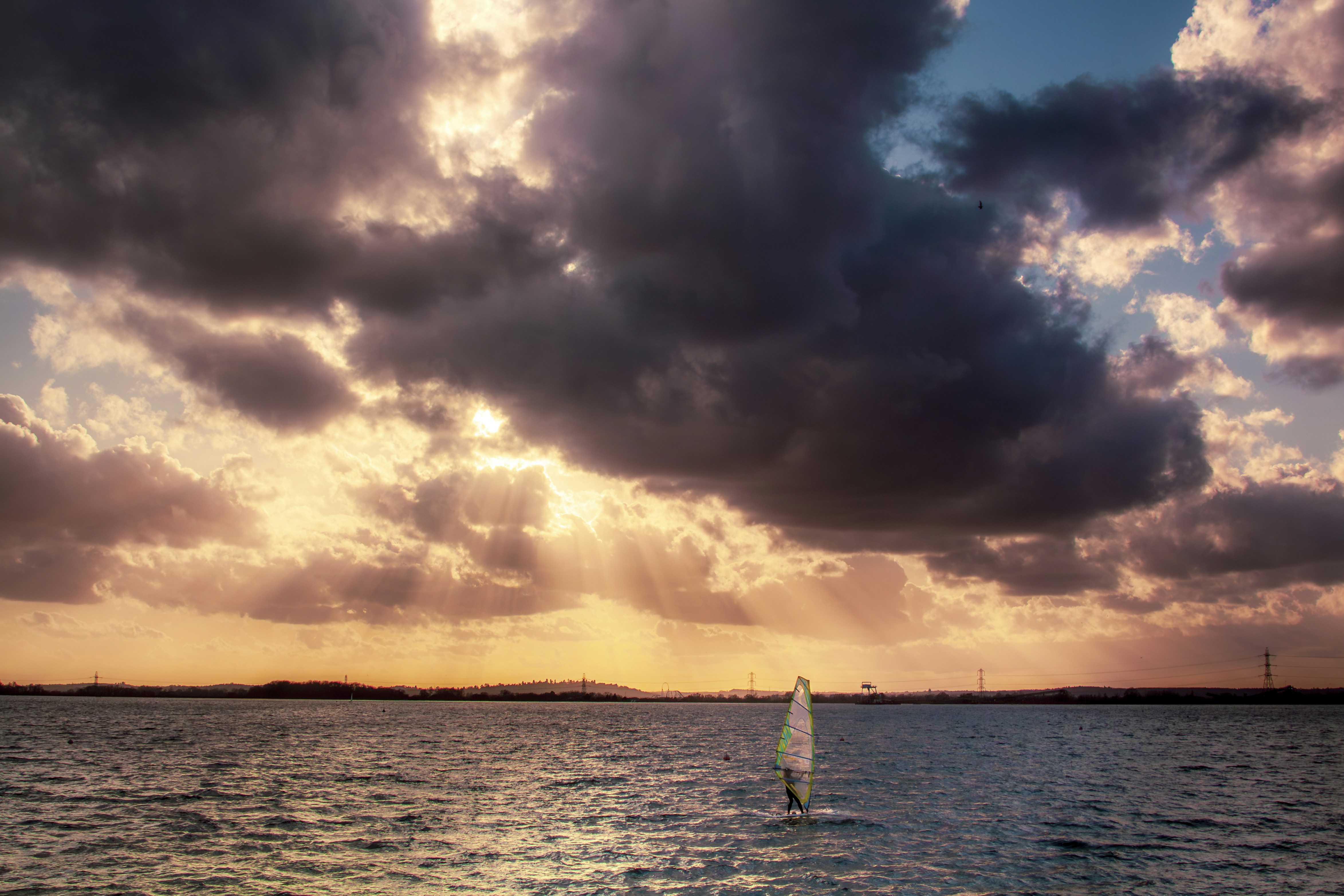 A sailboat in the water under a cloudy sky
