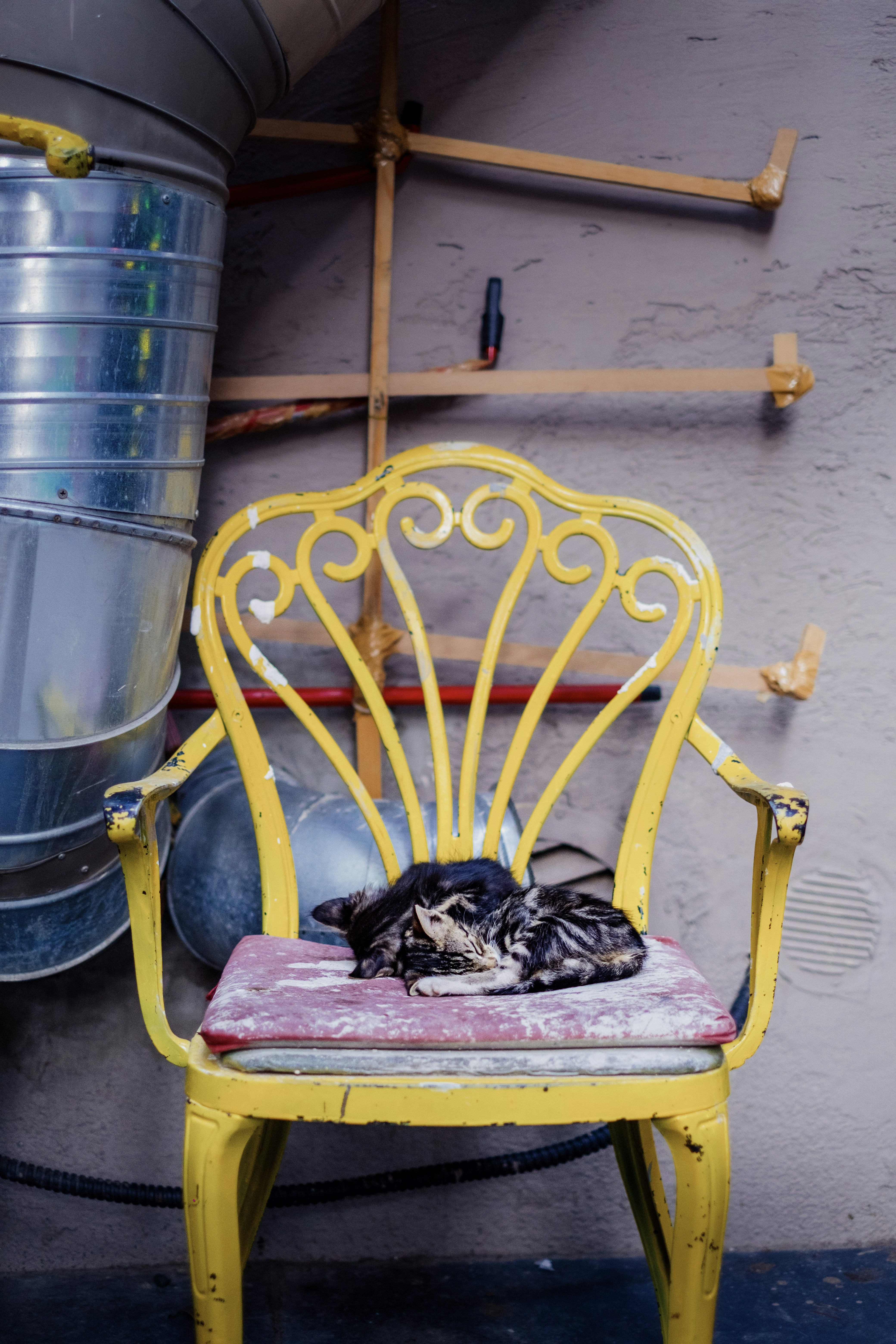 Ein gelber Stuhl sitzt neben einem Metallfass