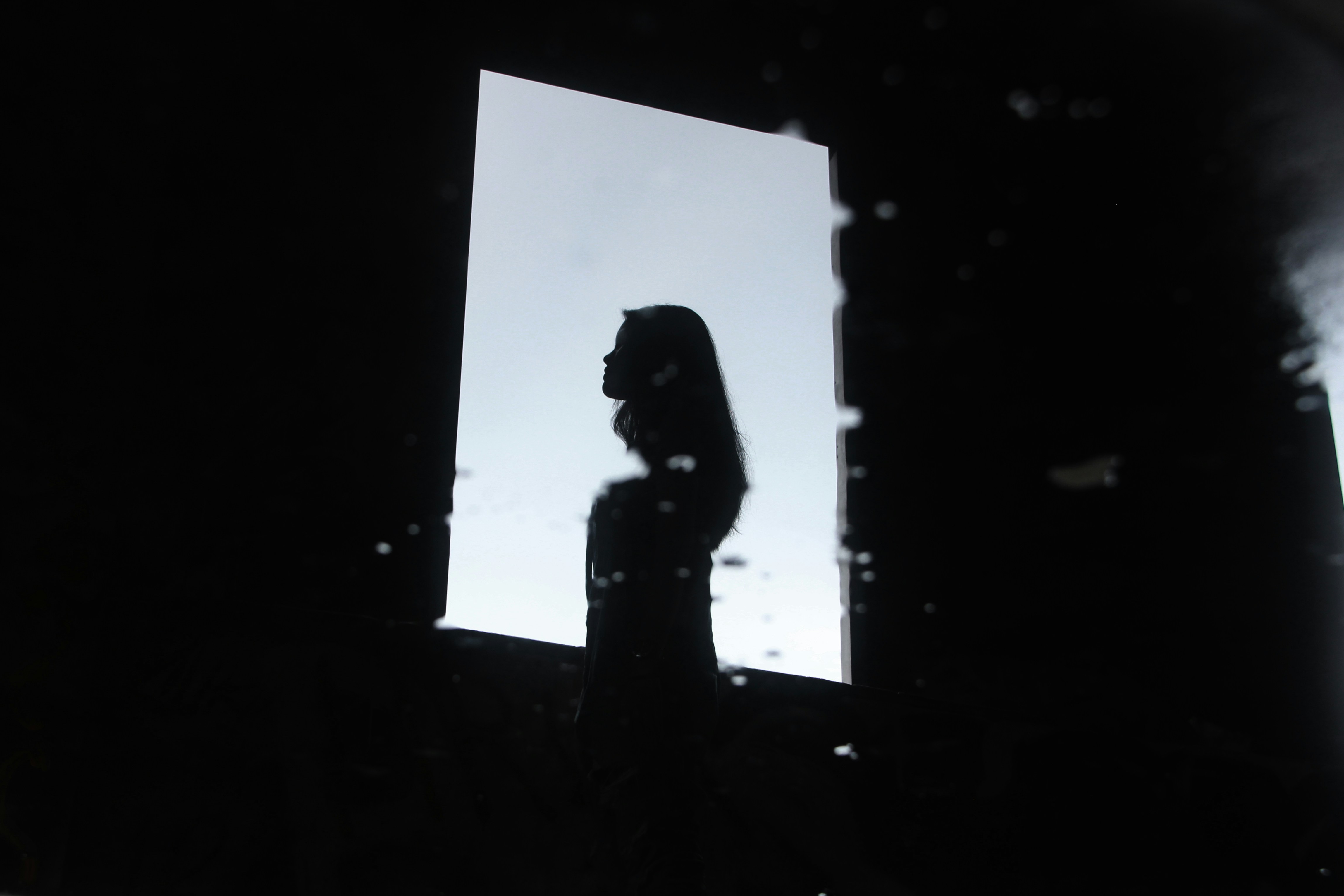 A silhouette of a person standing in front of a window
