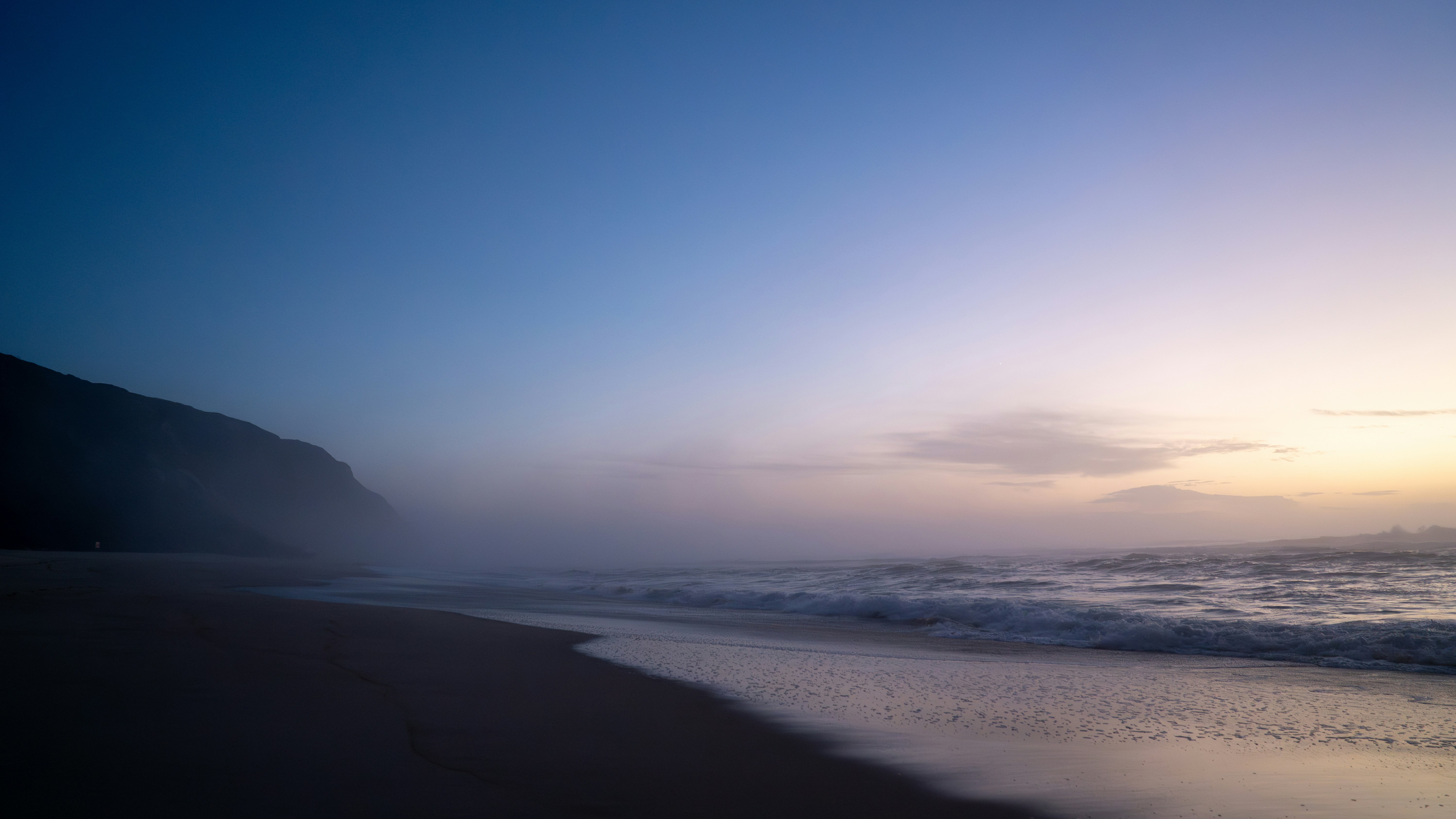 A blurry photo of a beach with waves coming in