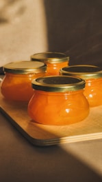 Three jars of orange jam sitting on a cutting board