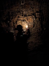 A man standing in a dark tunnel holding a light