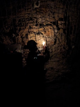 A man standing in a dark tunnel holding a light