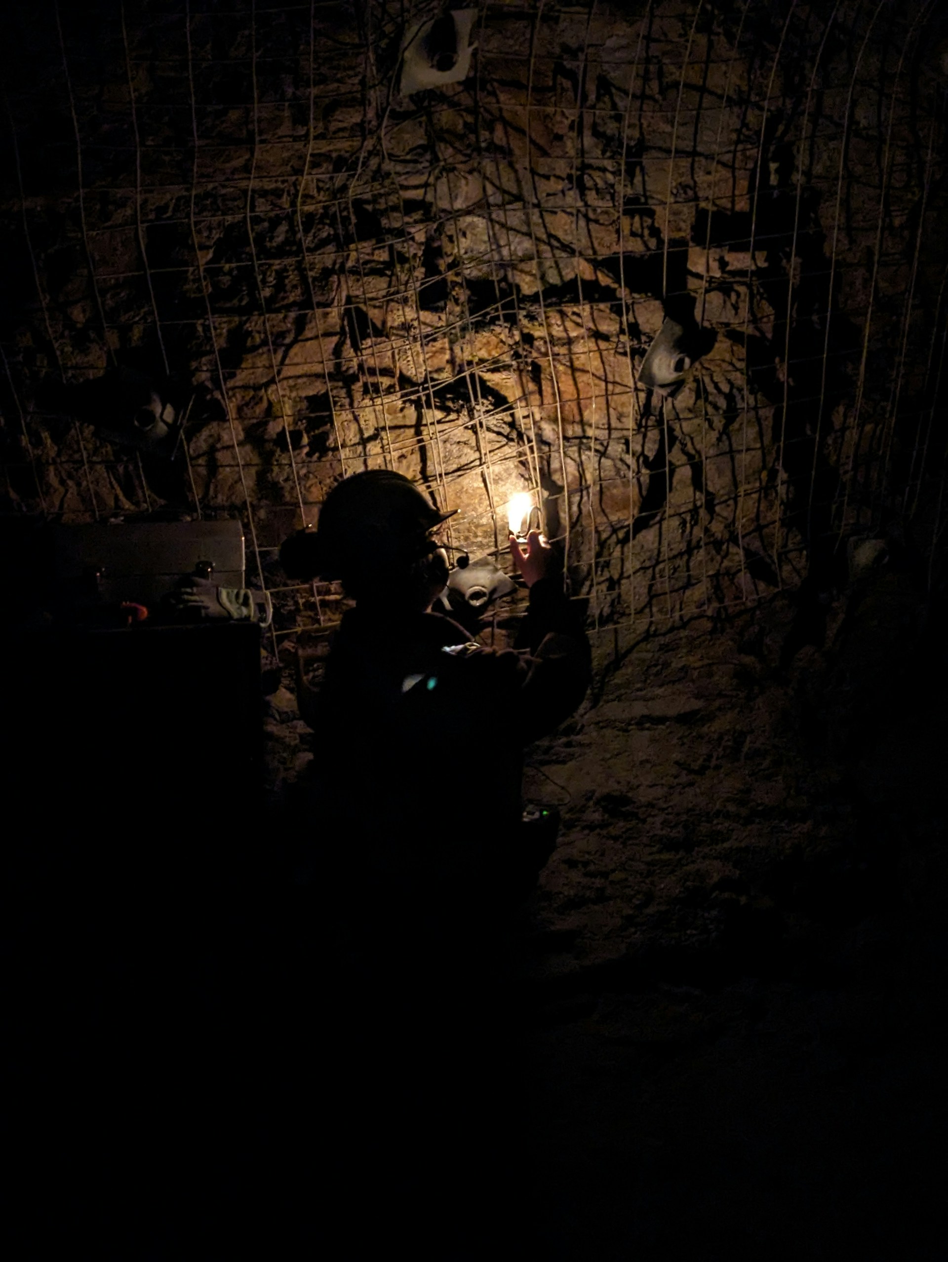 A man standing in a dark tunnel holding a light