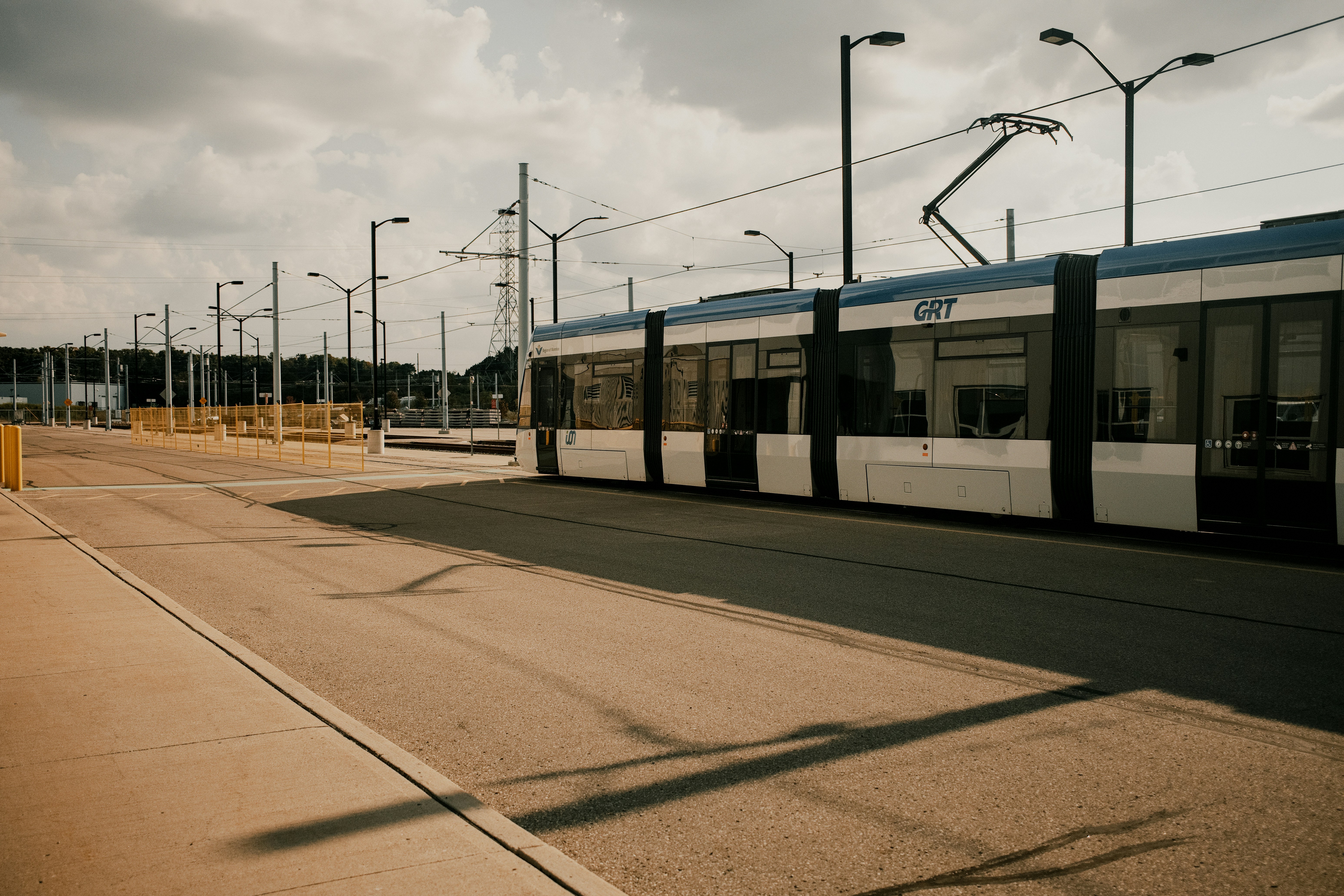 A train traveling past a train station under a cloudy sky