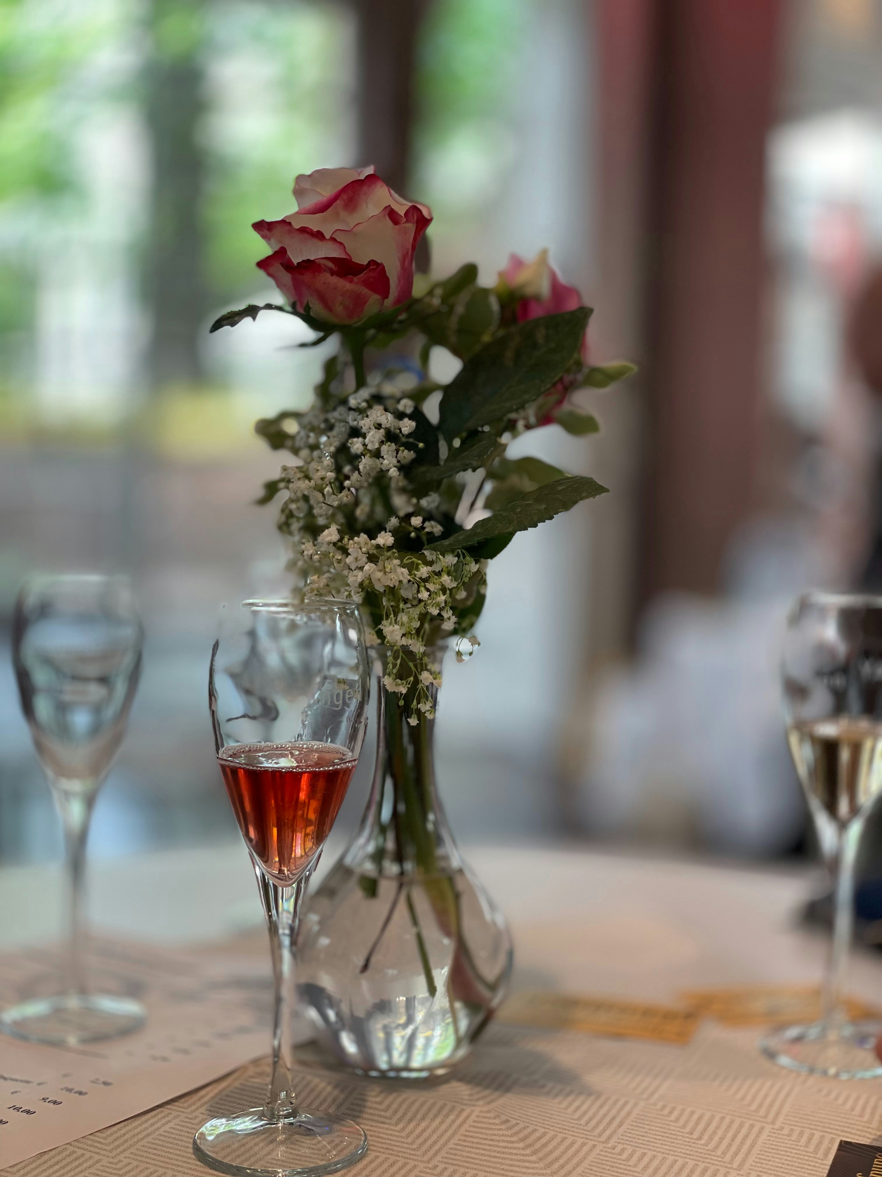 A table with a vase of flowers and wine glasses