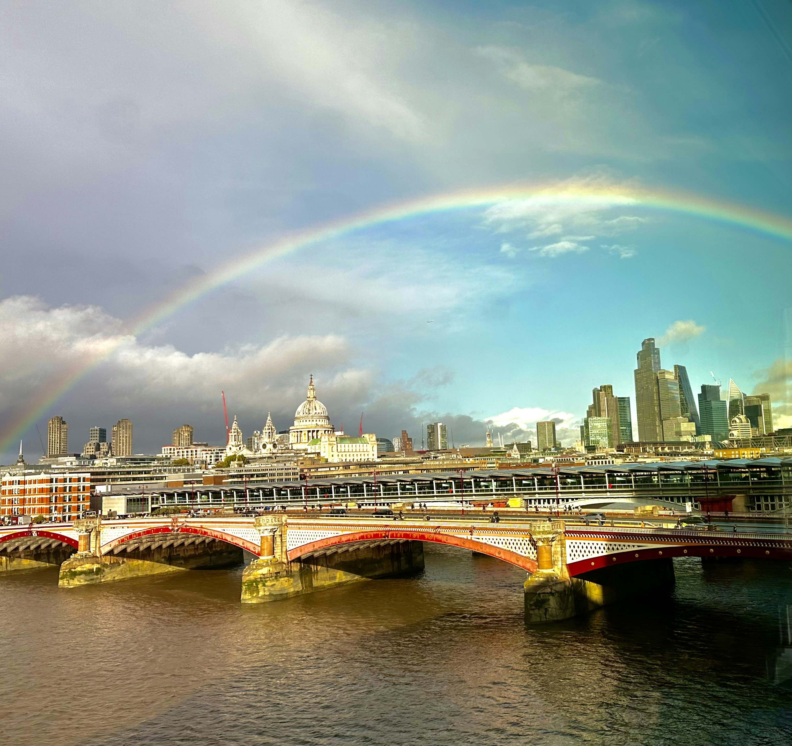 A rainbow over a city with a bridge