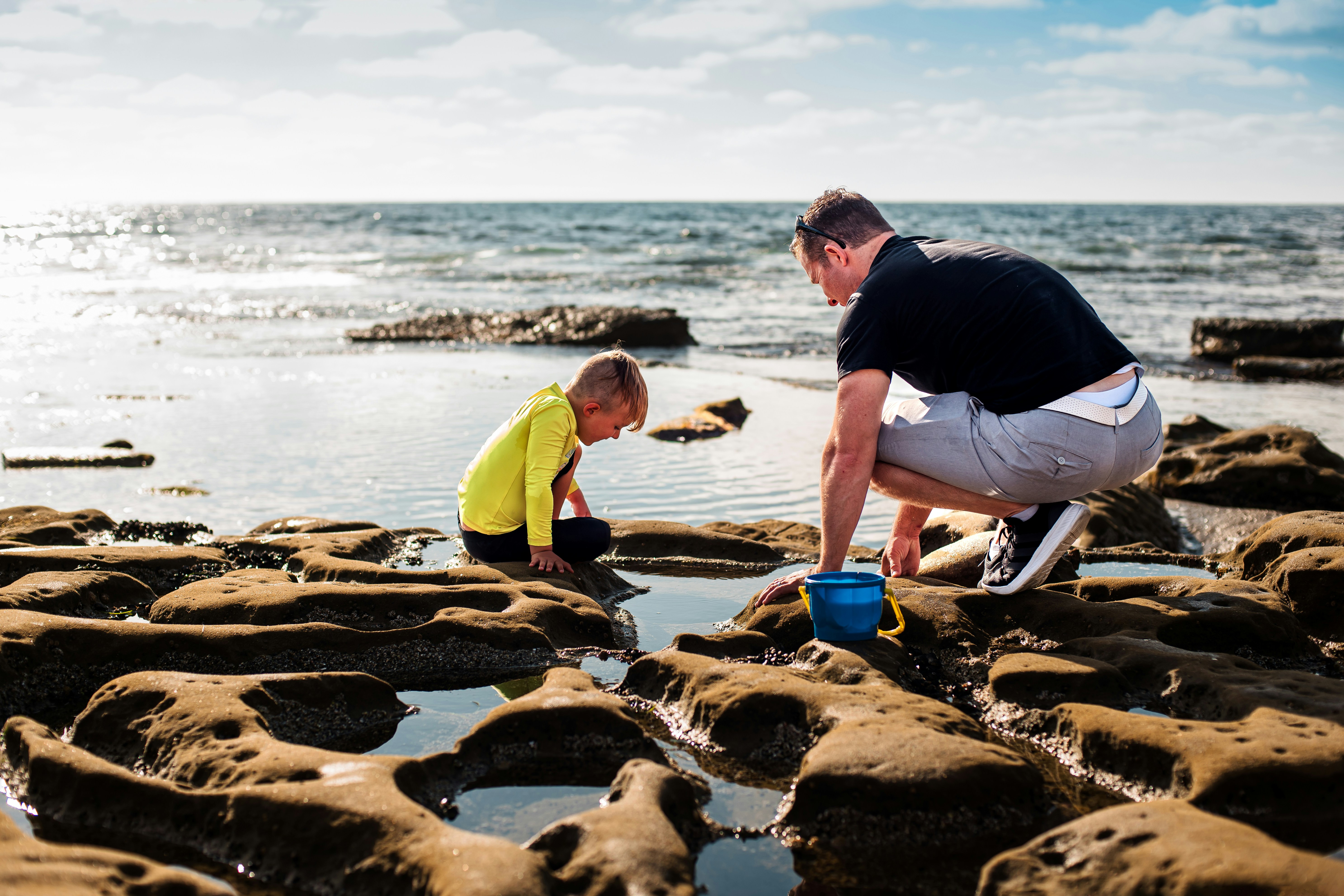 A man and a boy are playing on the rocks at the beach