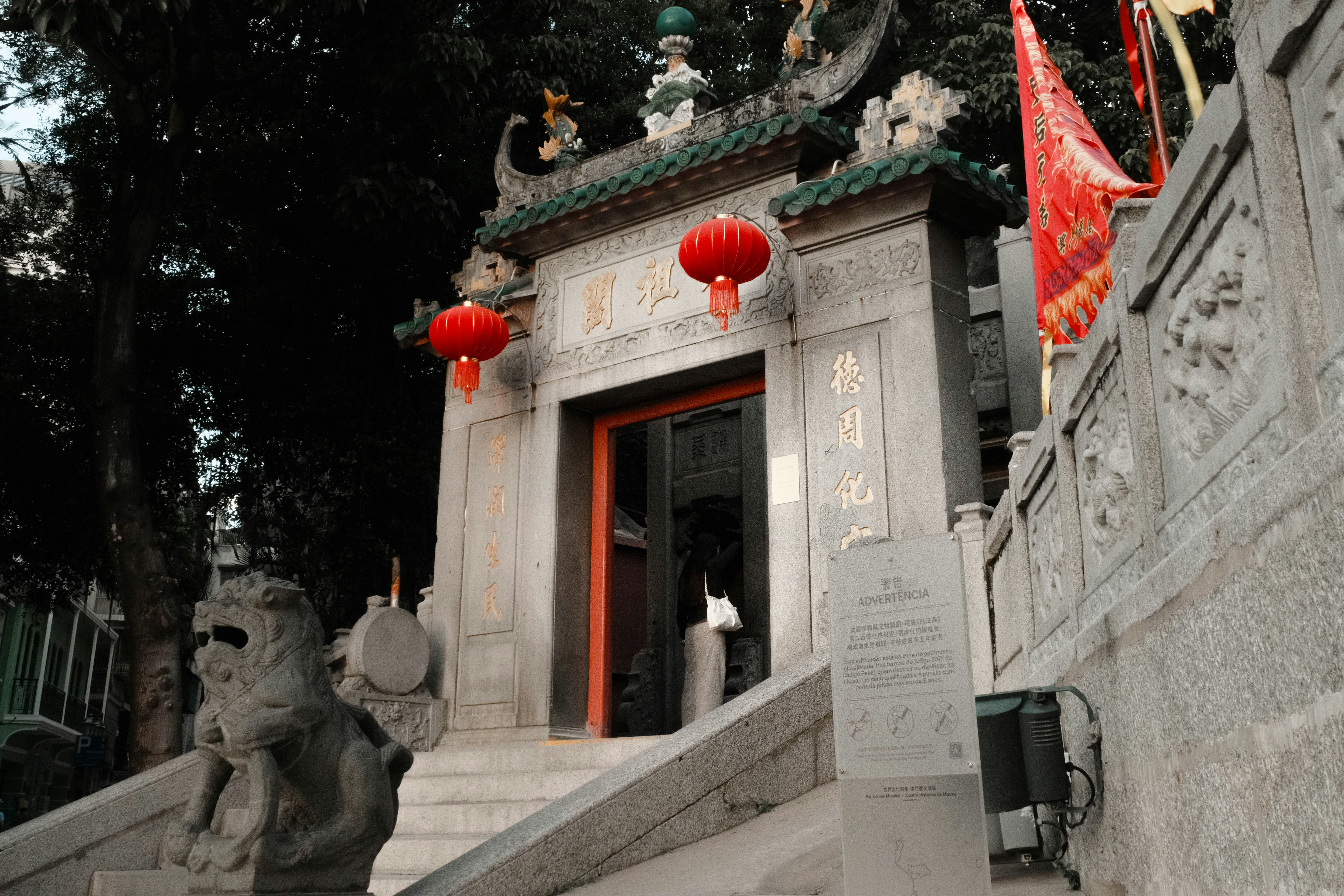 A stone building with red lanterns hanging from it's roof