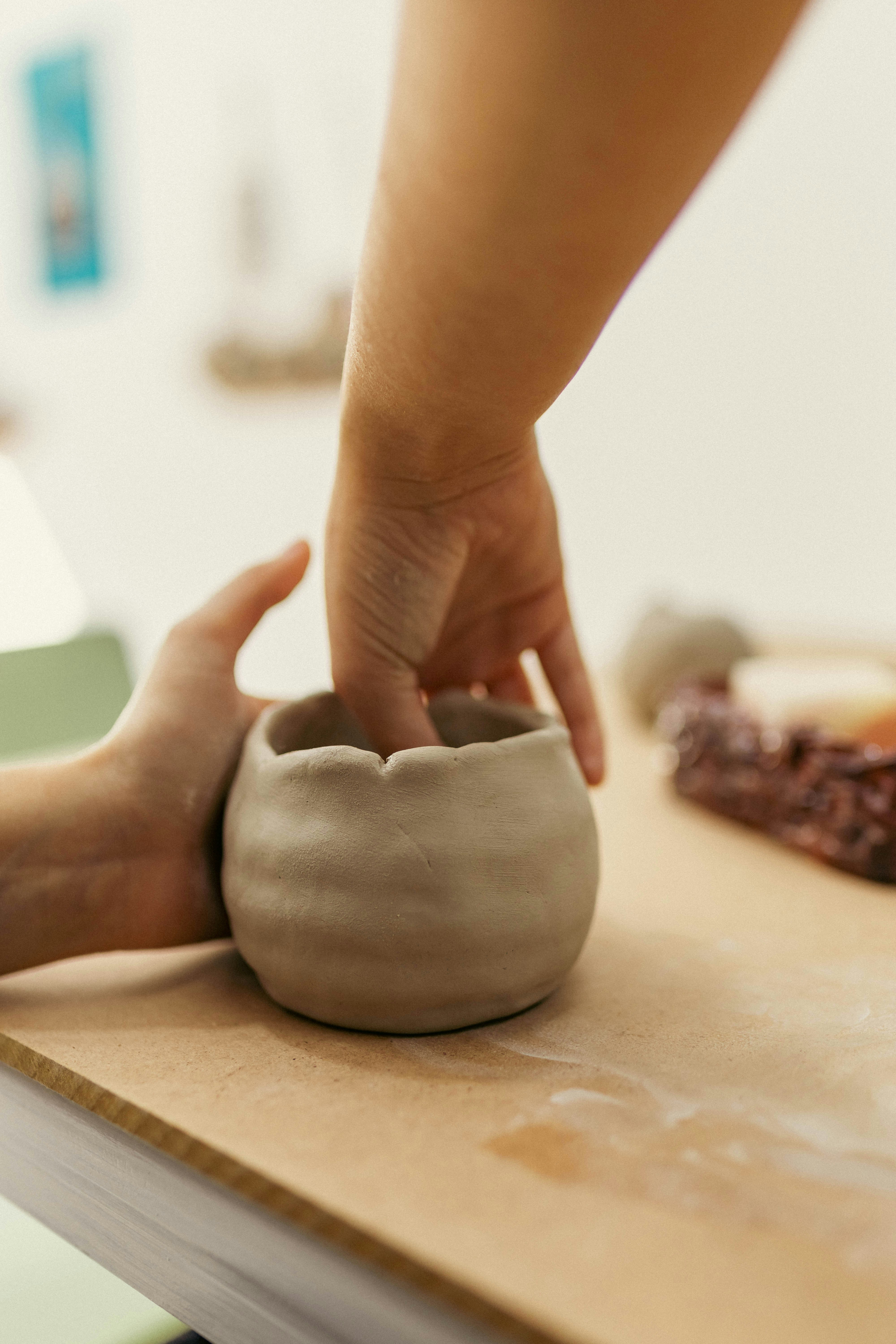 A person is kneading a clay pot on a table