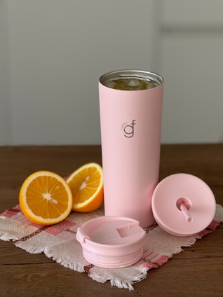 A pink tumbler next to some sliced oranges