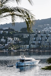 MG TURIZM A white boat in a body of water with a city in the background