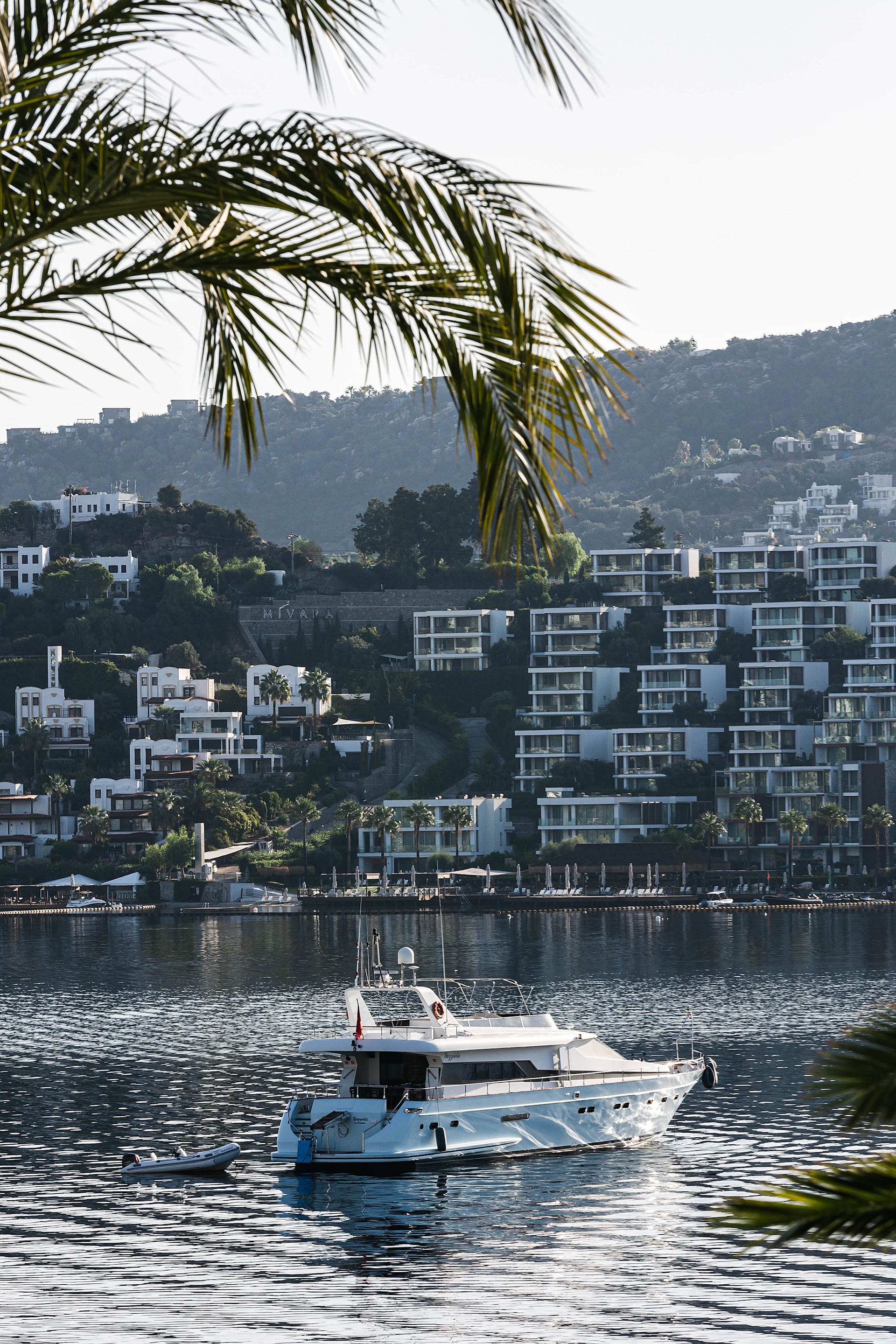 A white boat in a body of water with a city in the background