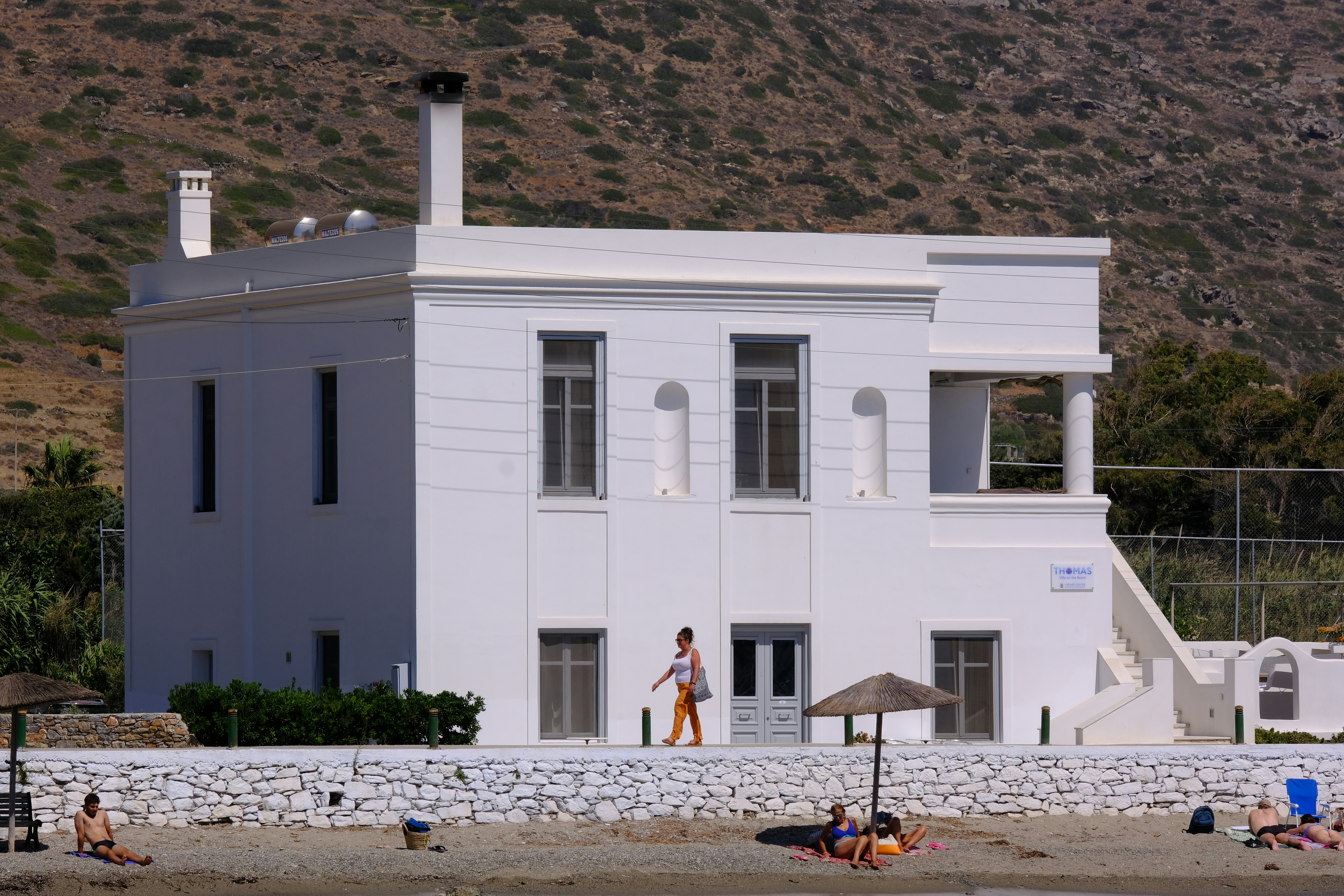 A large white house sitting on top of a beach, 
