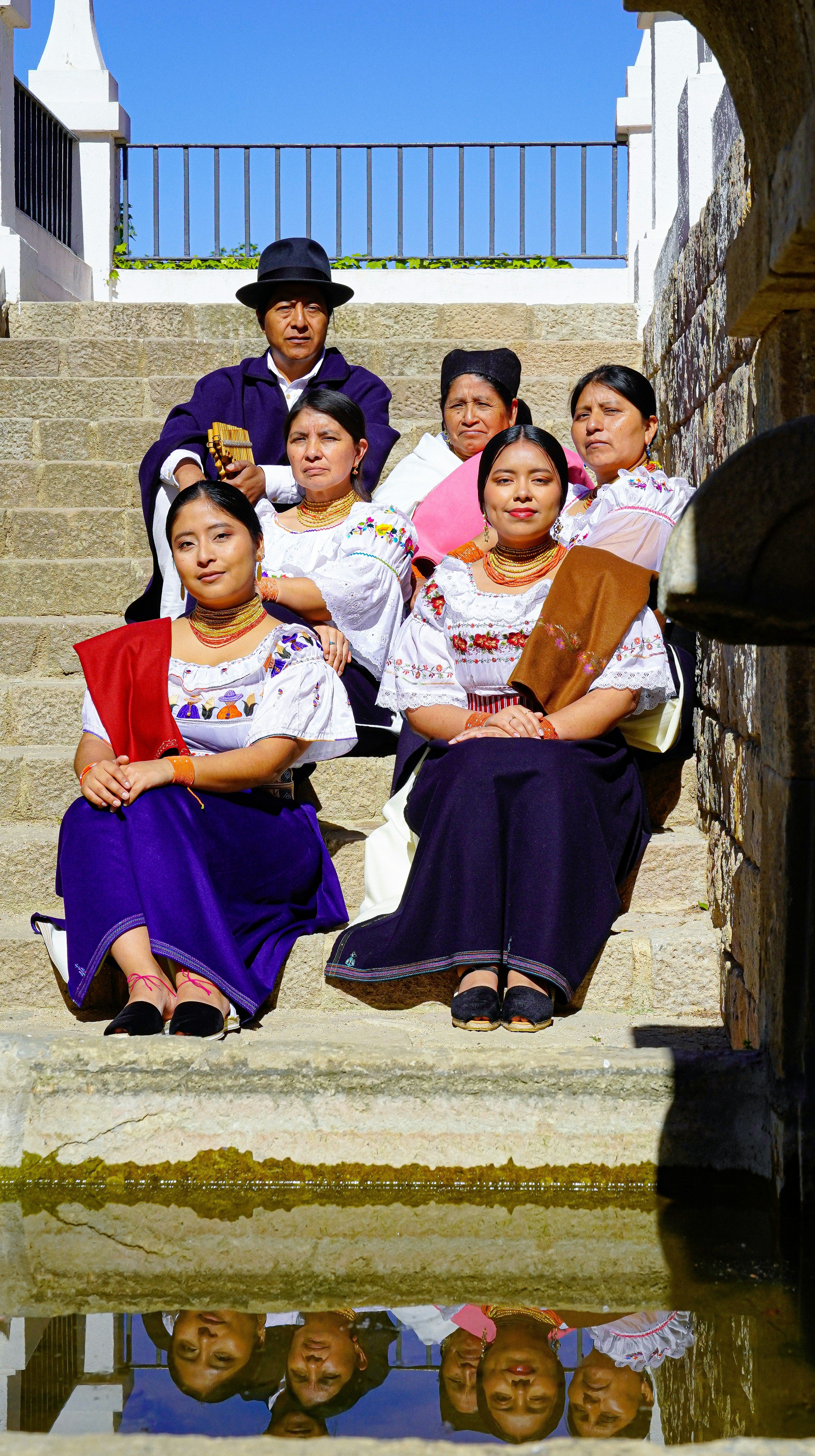 A group of people sitting on steps next to a body of water