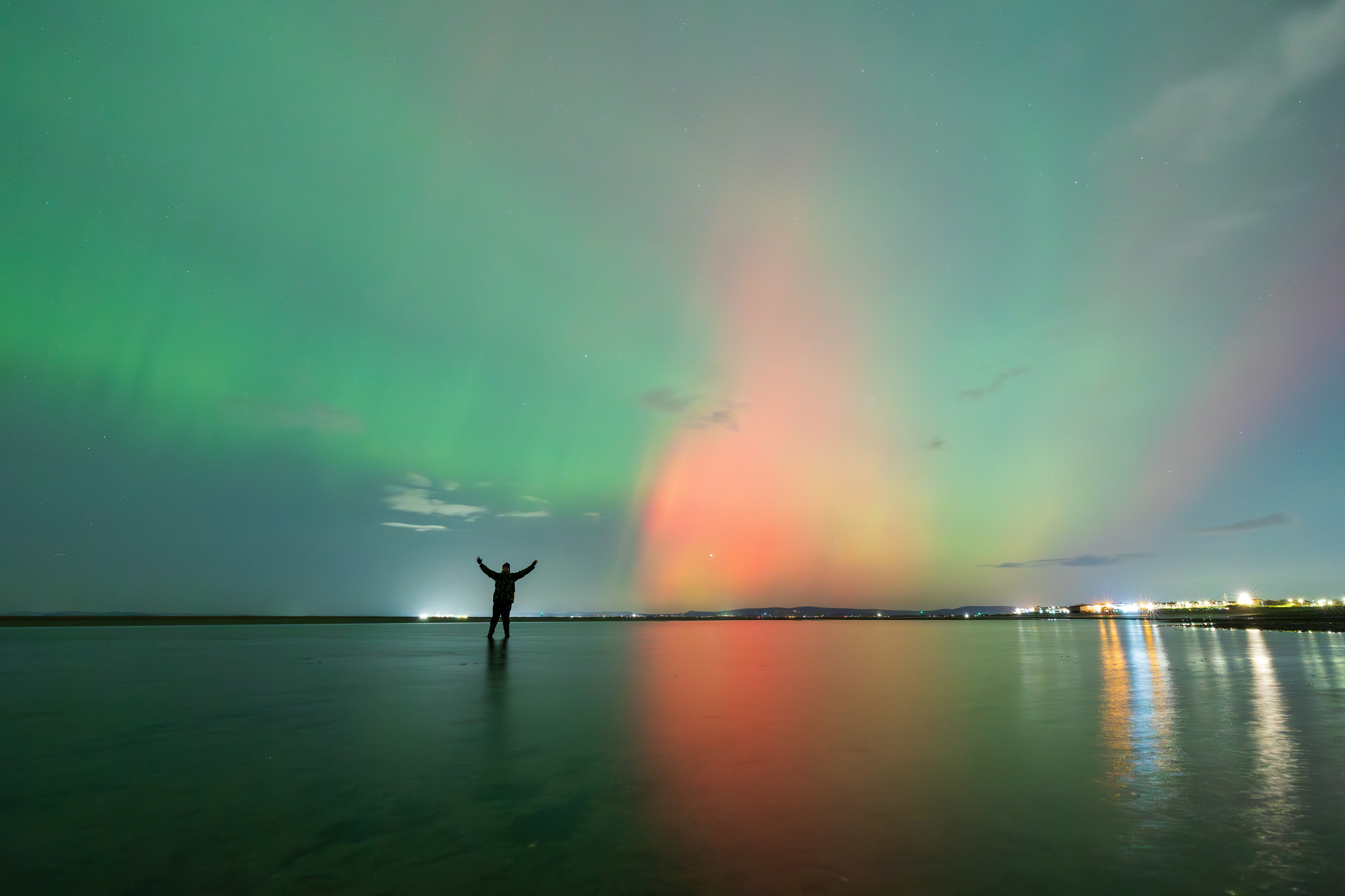 A person standing in the water with their arms in the air