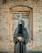 A woman wearing a black veil standing in front of a brick building