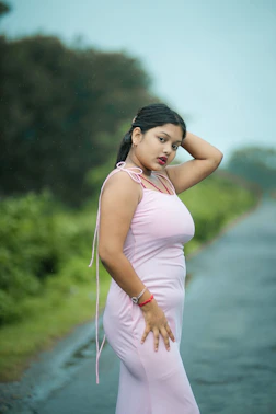A woman in a pink dress standing on the side of a road