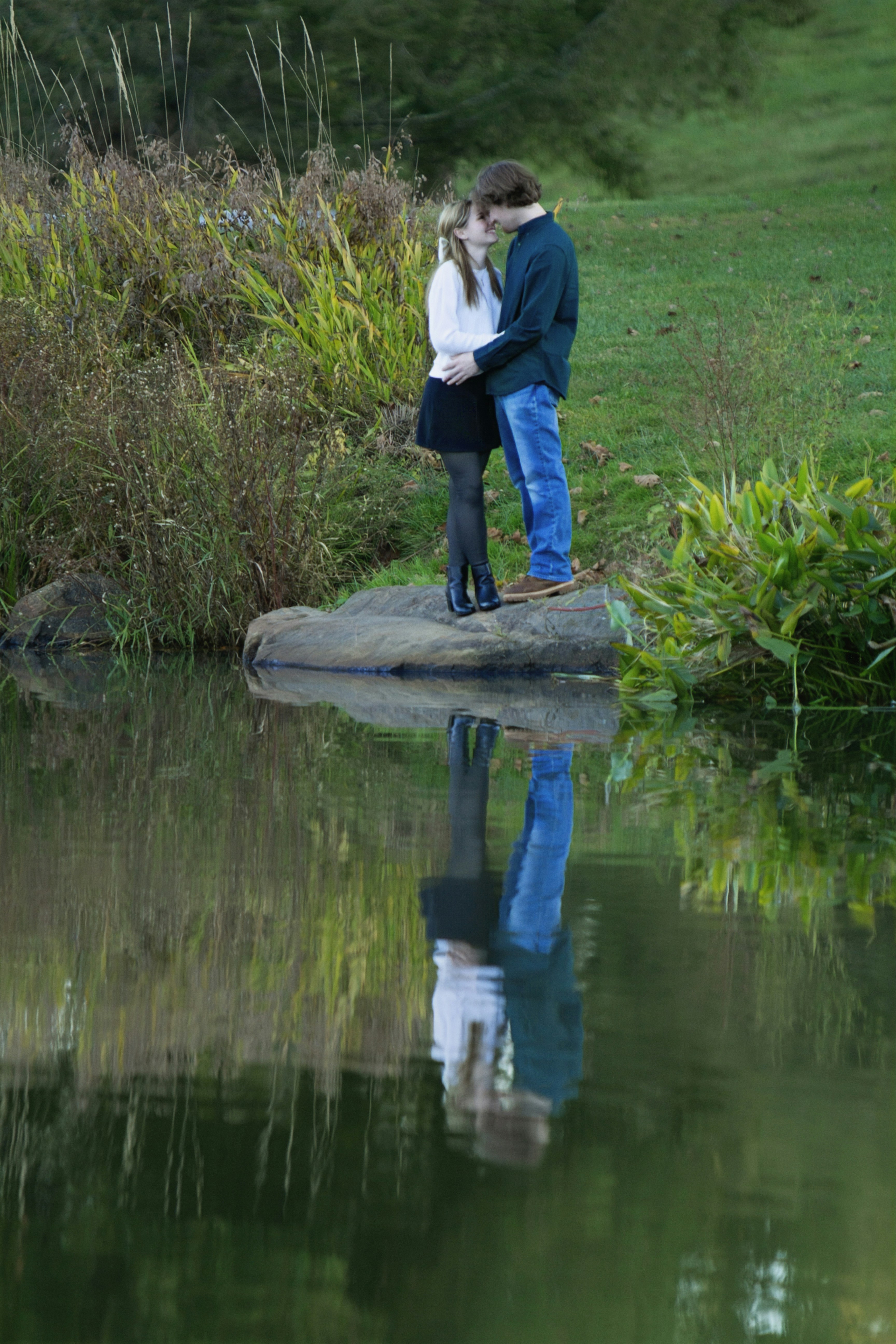 Ein Mann und eine Frau stehen auf einem Felsen am Wasser
