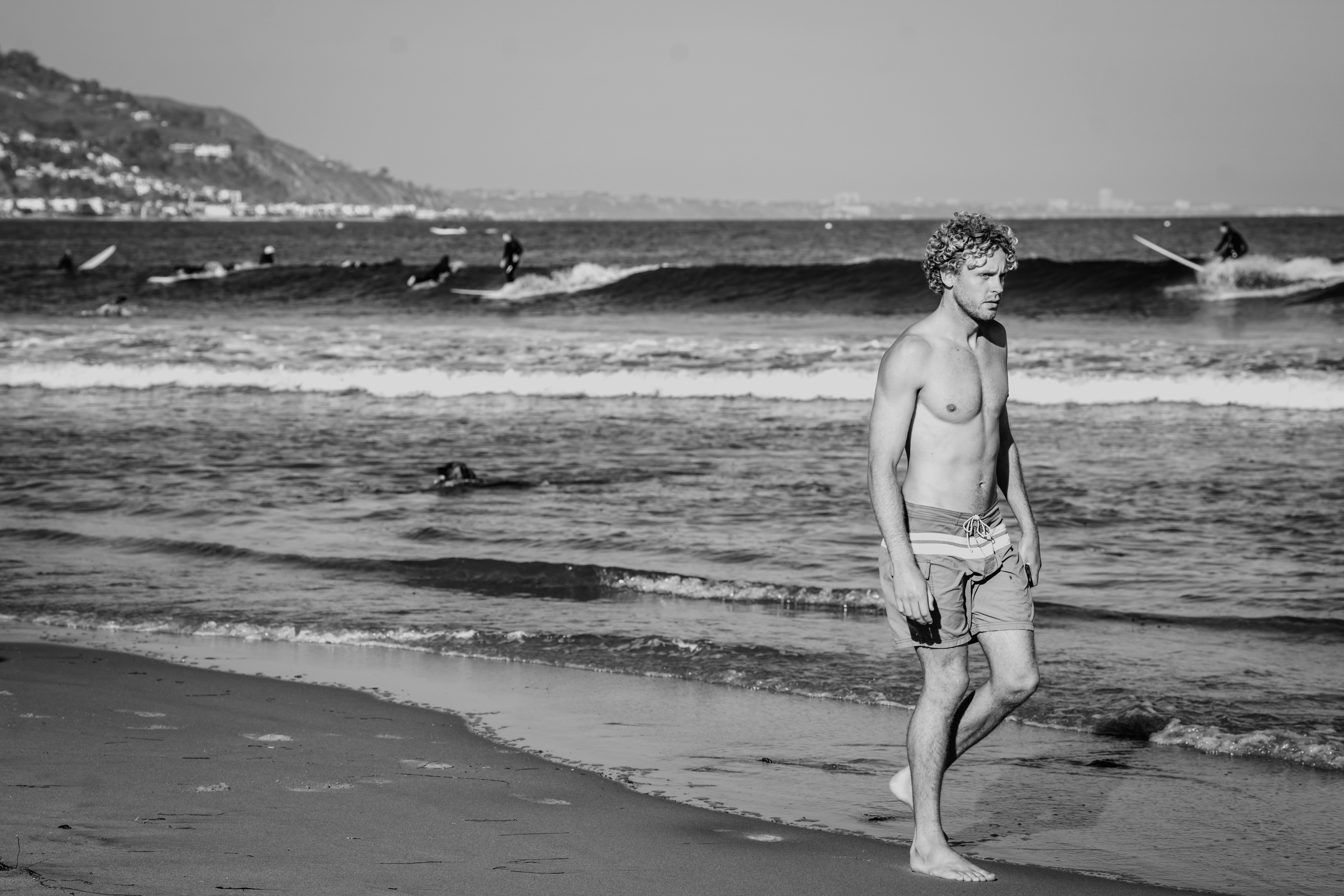 A man standing on top of a beach next to the ocean photo – Free Water ...