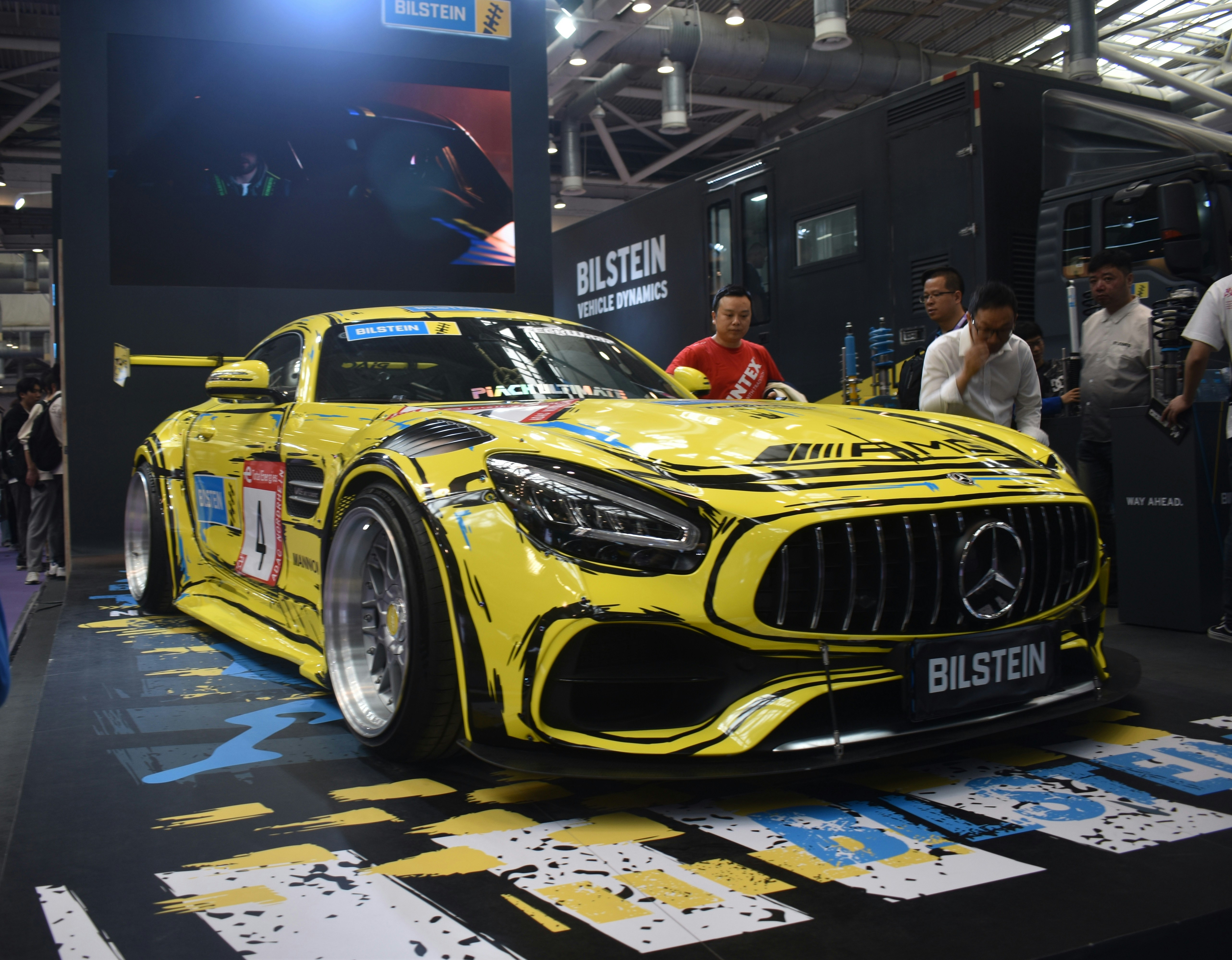 A yellow mercedes sports car on display at a car show