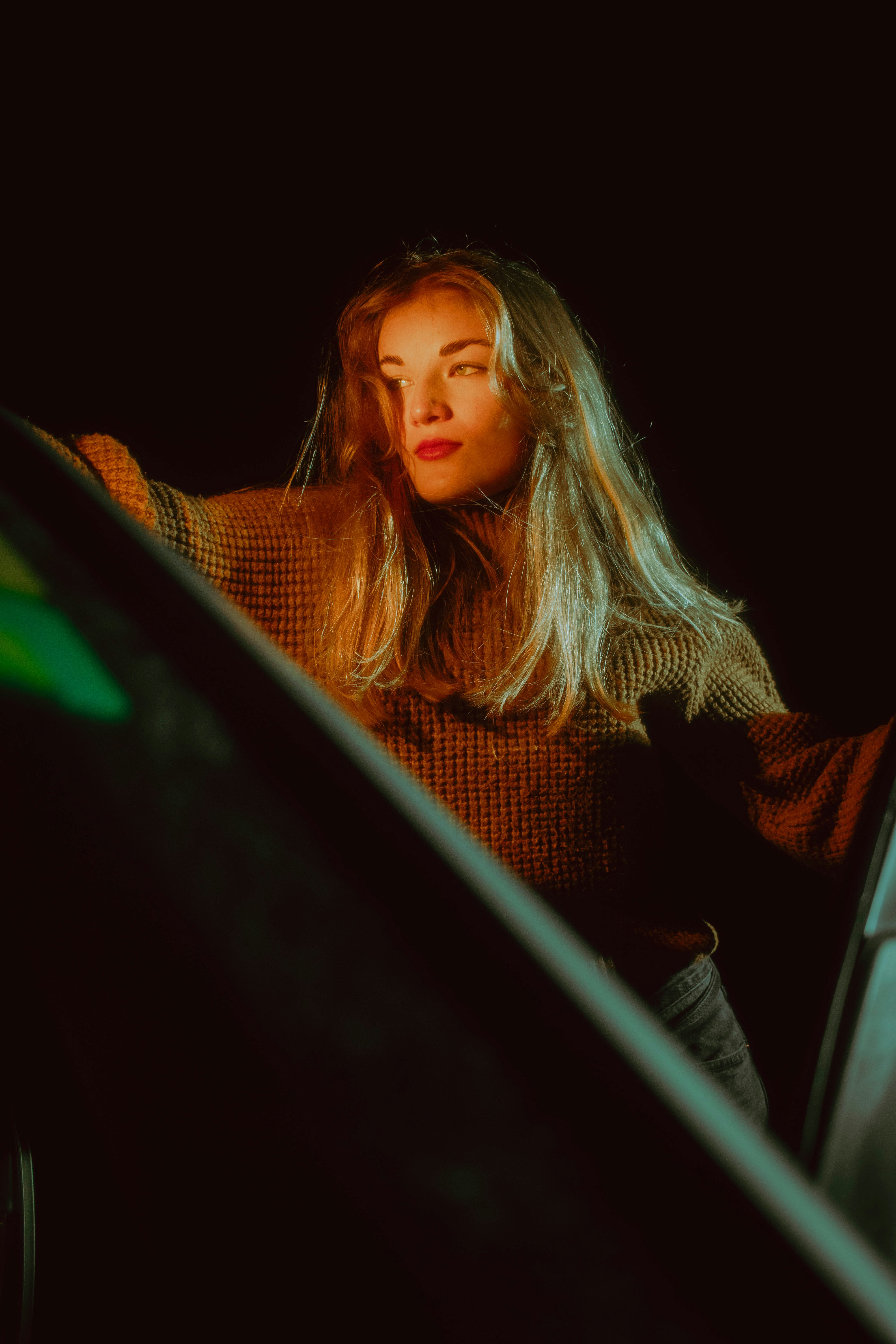 A woman standing next to a car in the dark