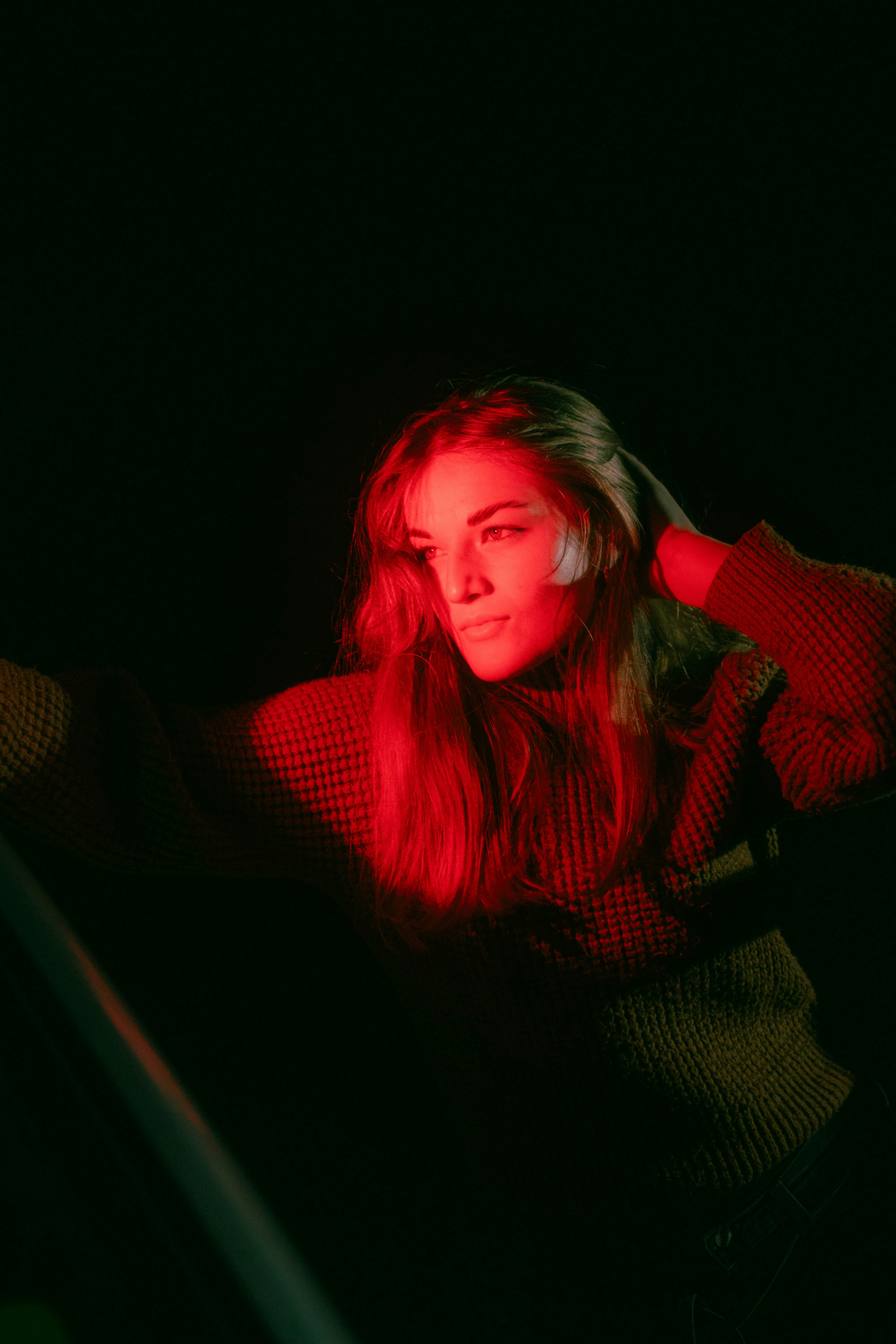 A woman sitting in the dark with her hand on her head