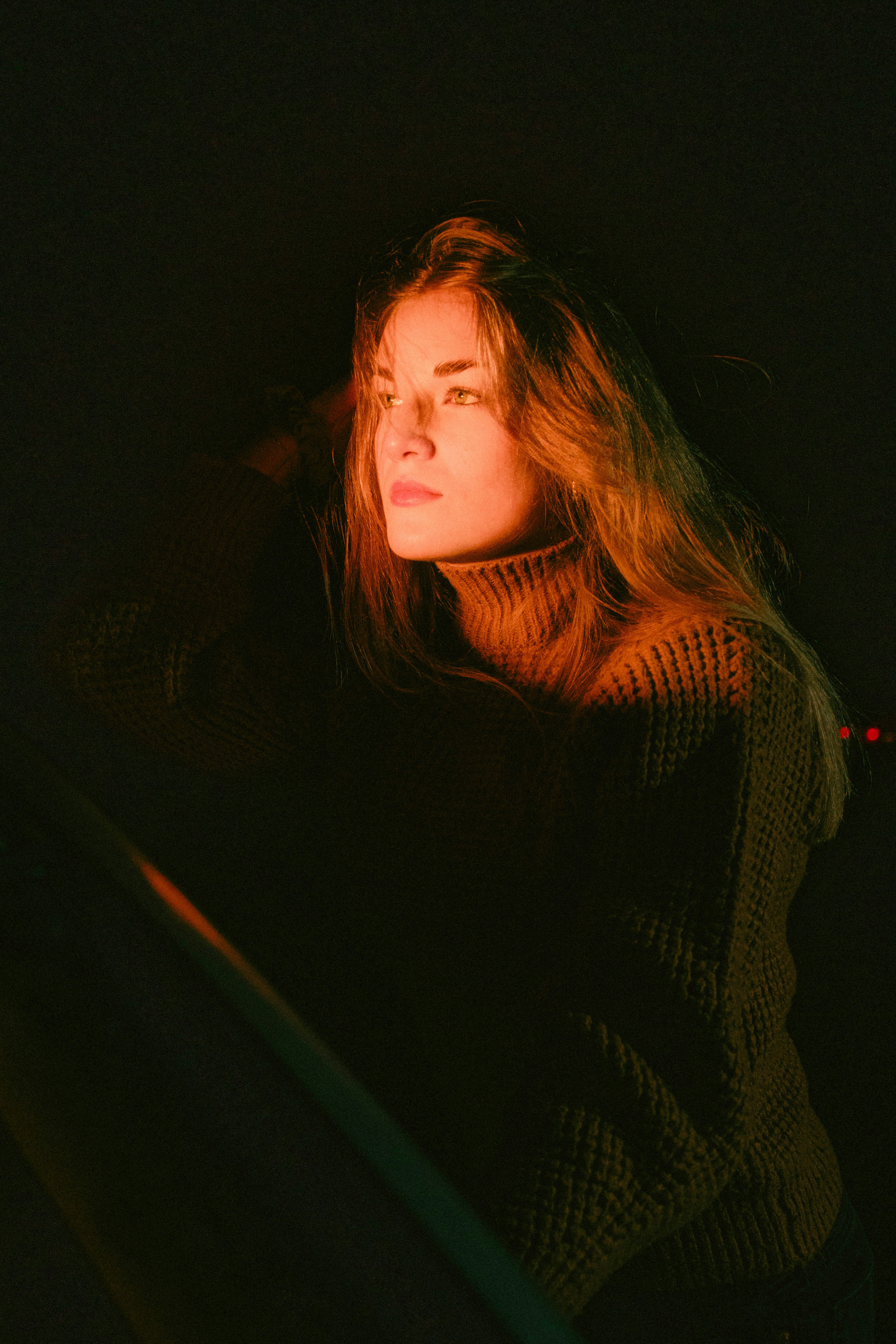 A woman standing in the dark with her eyes closed