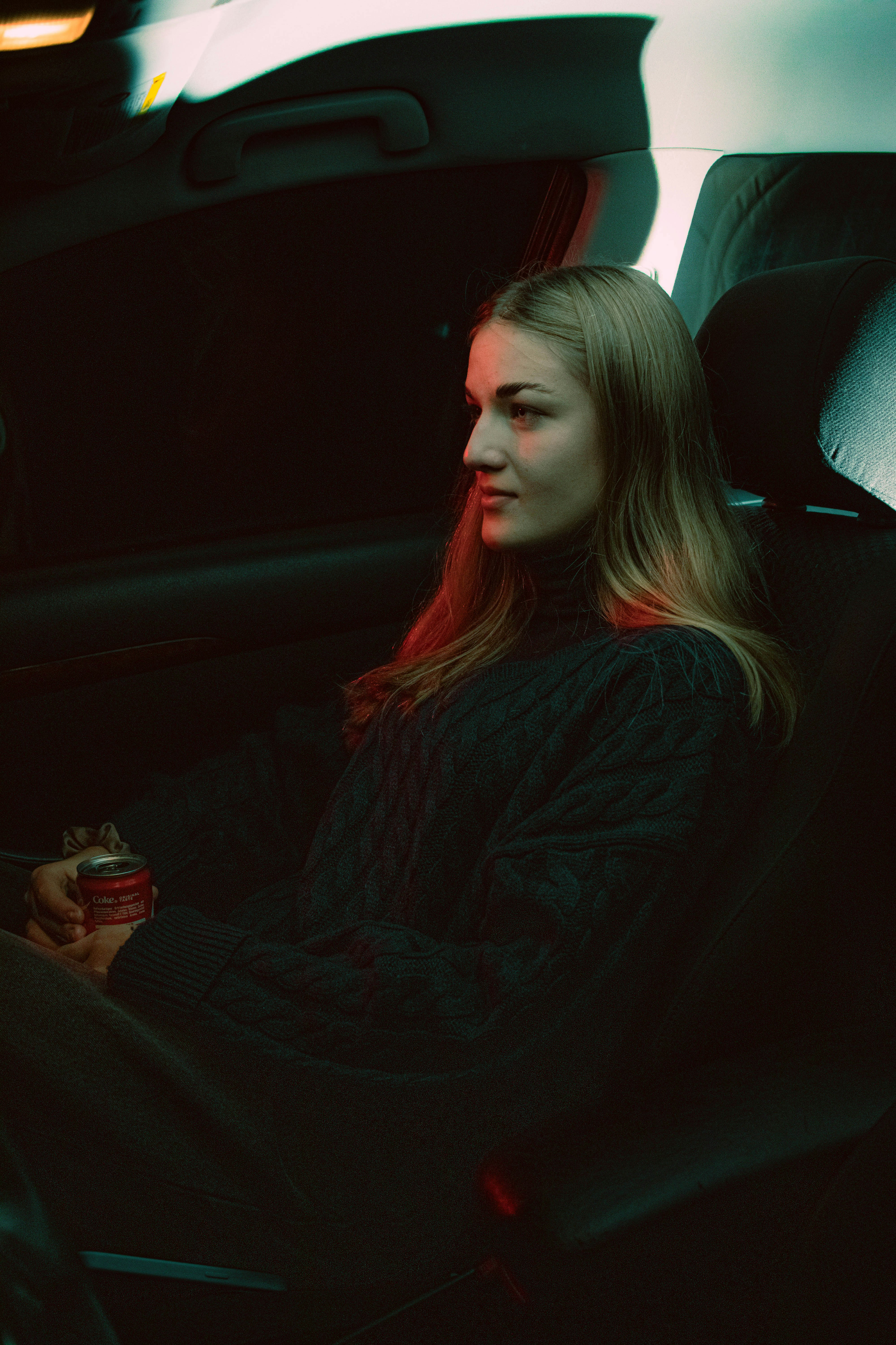 A woman sitting in a car holding a drink