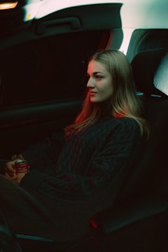 A woman sitting in a car holding a drink