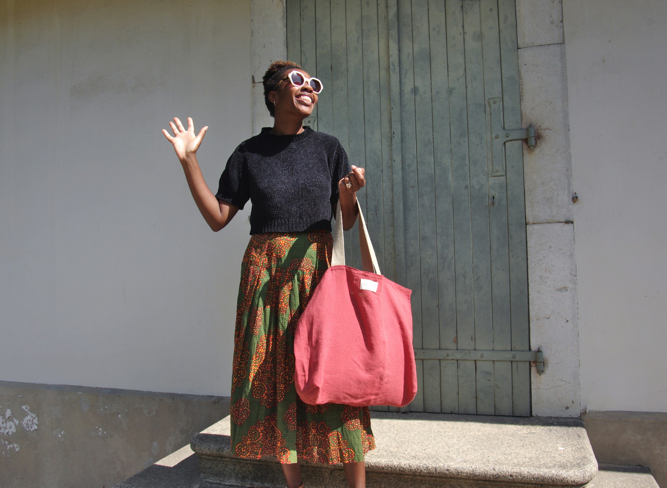 A woman holding a pink bag and waving