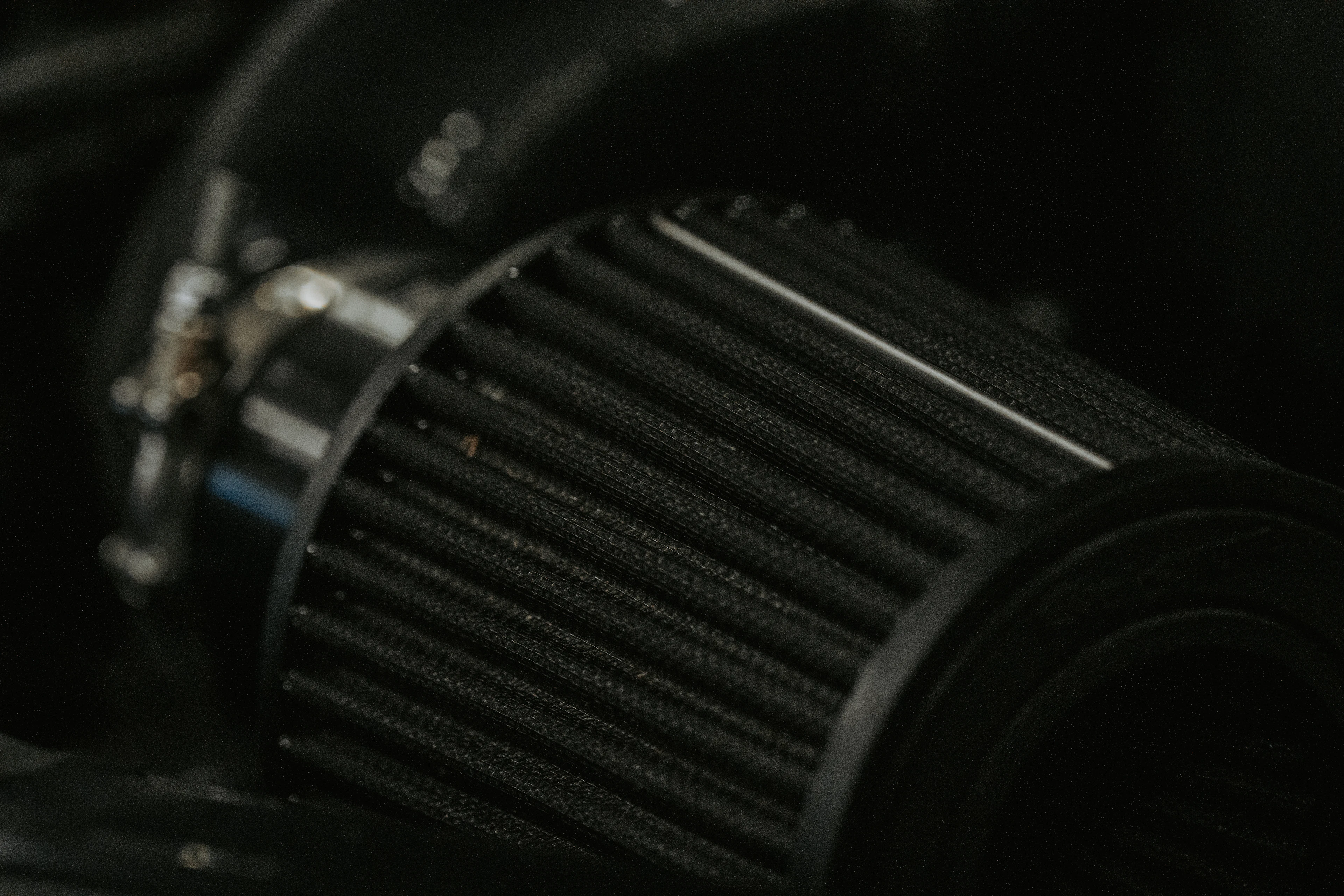 A black cone-shaped pod air filter fitted to a motorcycle's intake
