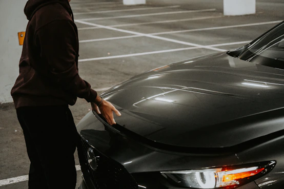 A person standing next to a car in a parking lot