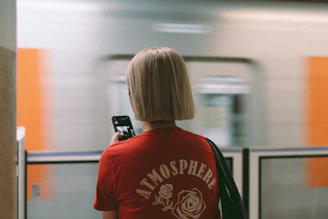 A woman in a red shirt is looking at her cell phone