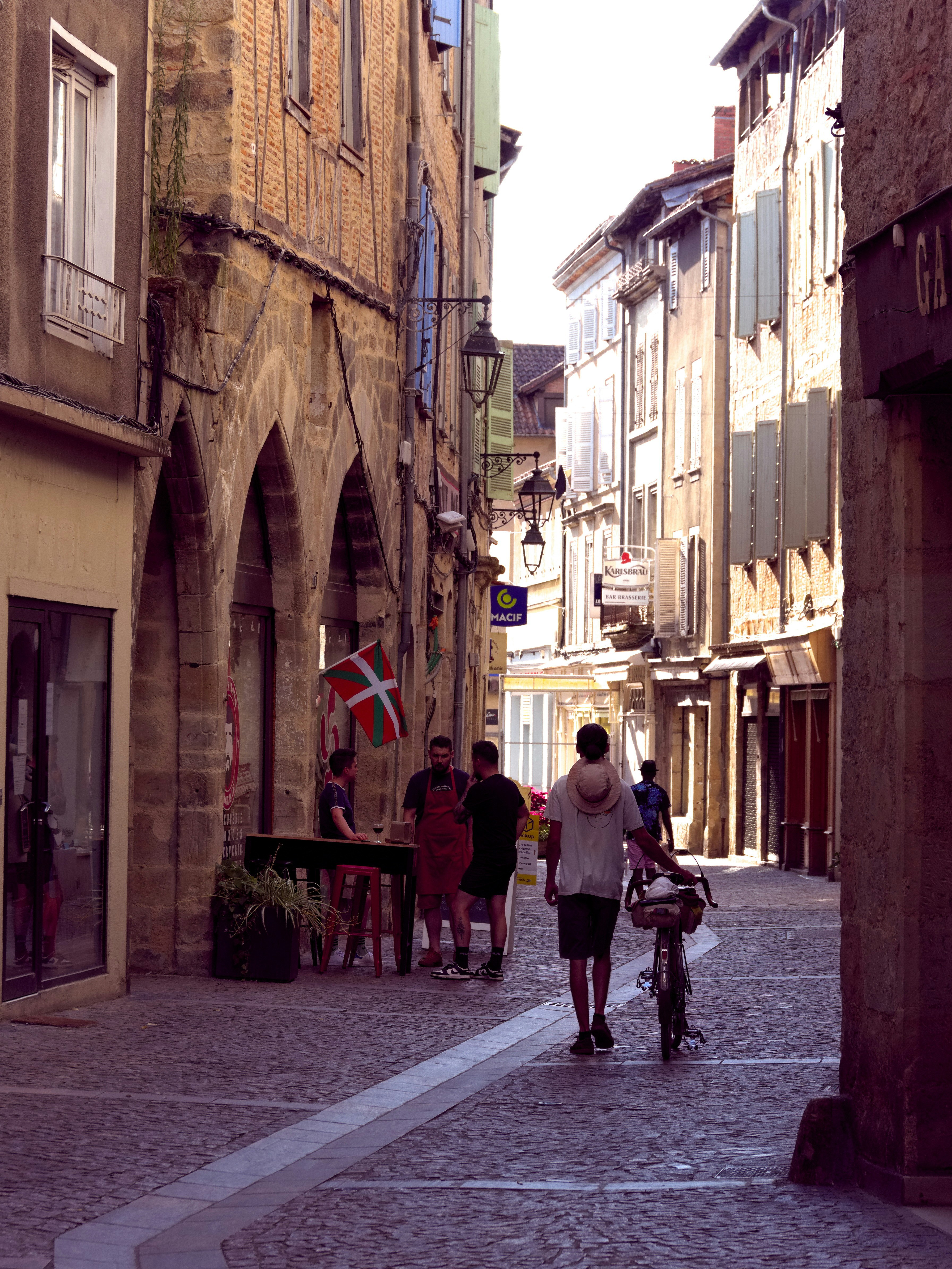 A man walking down a street next to tall buildings