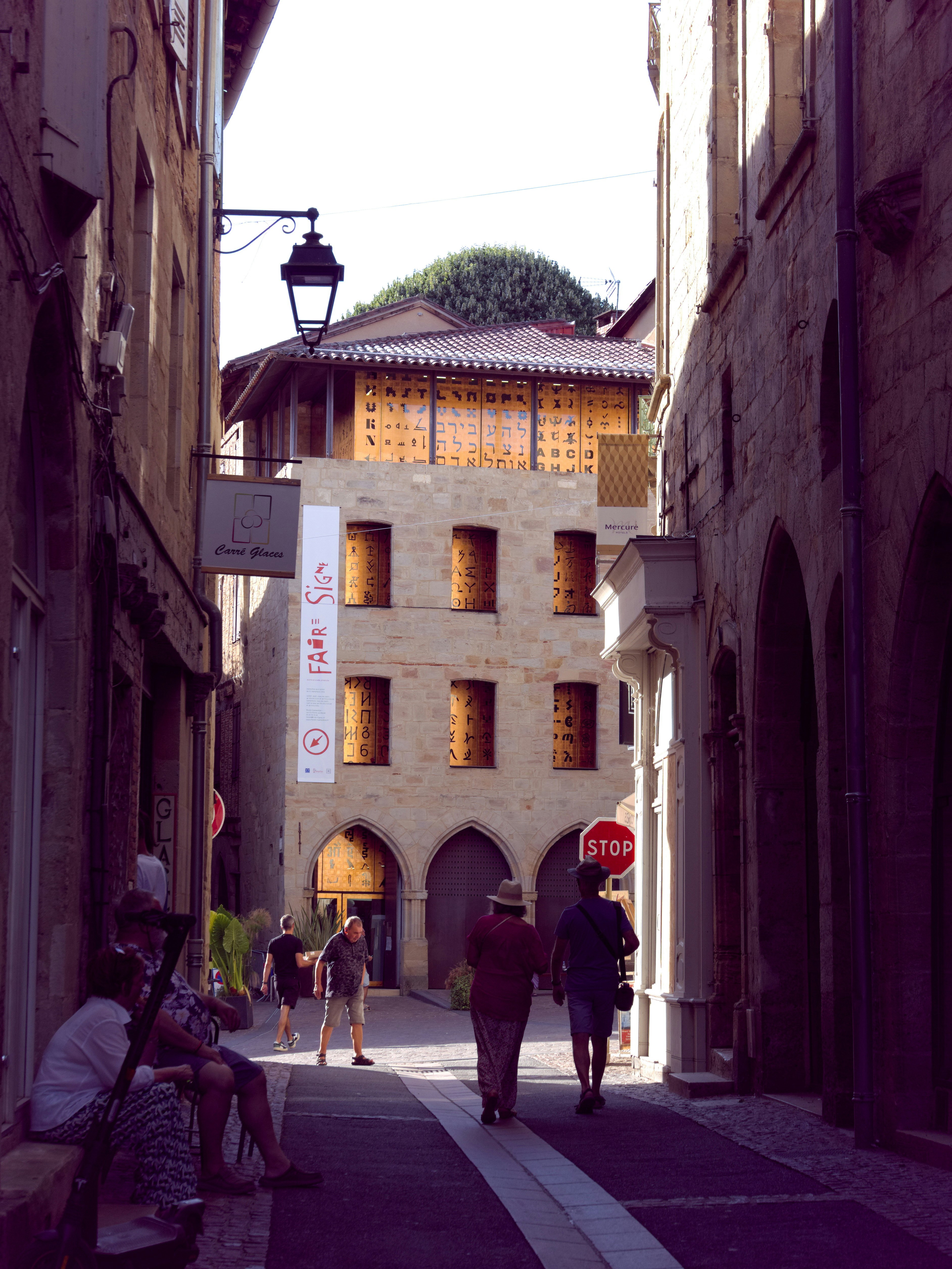 A group of people walking down a street next to tall buildings