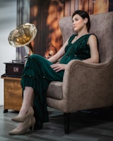 A woman in a green dress sitting in a chair