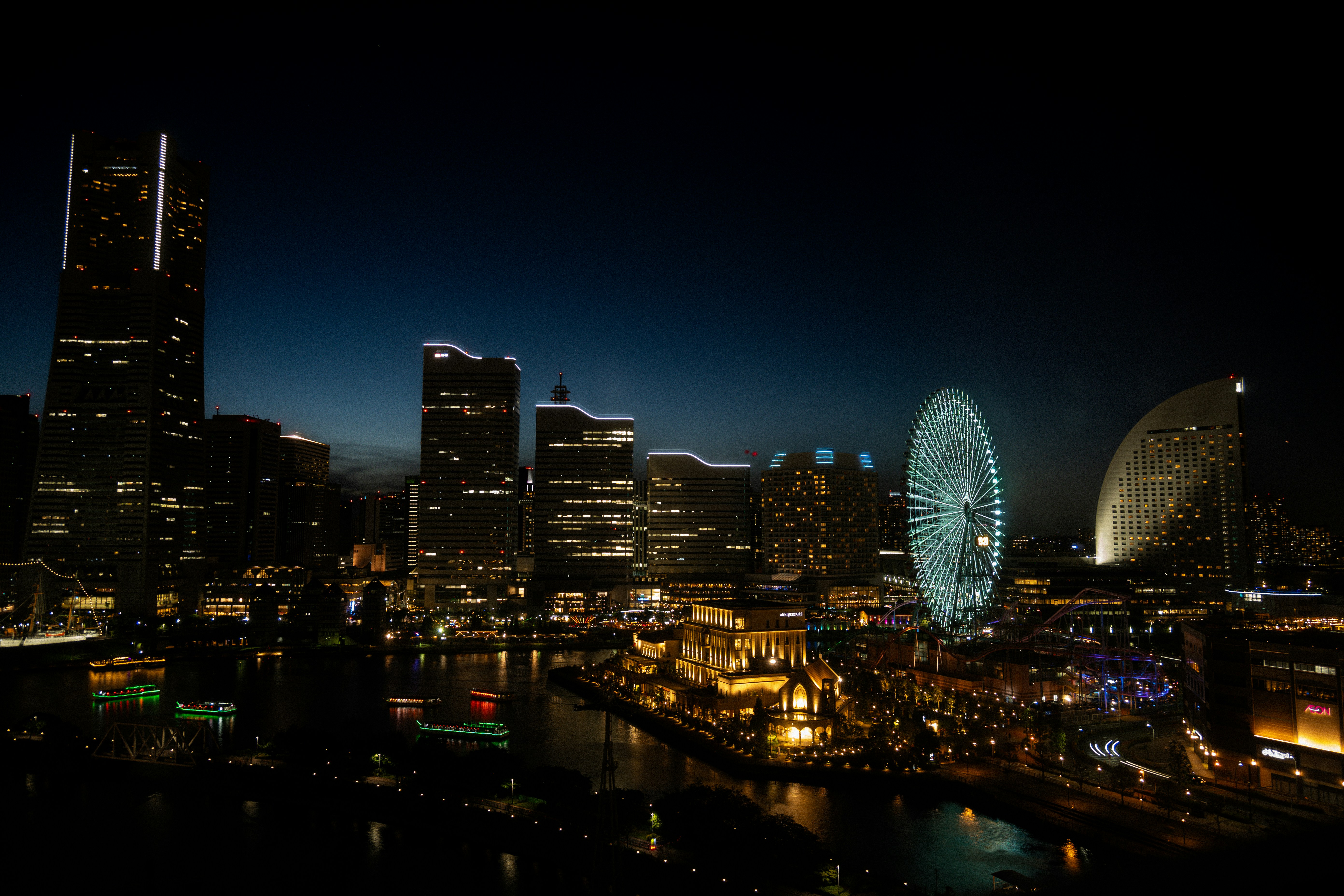 A view of a city at night with a ferris wheel in the foreground