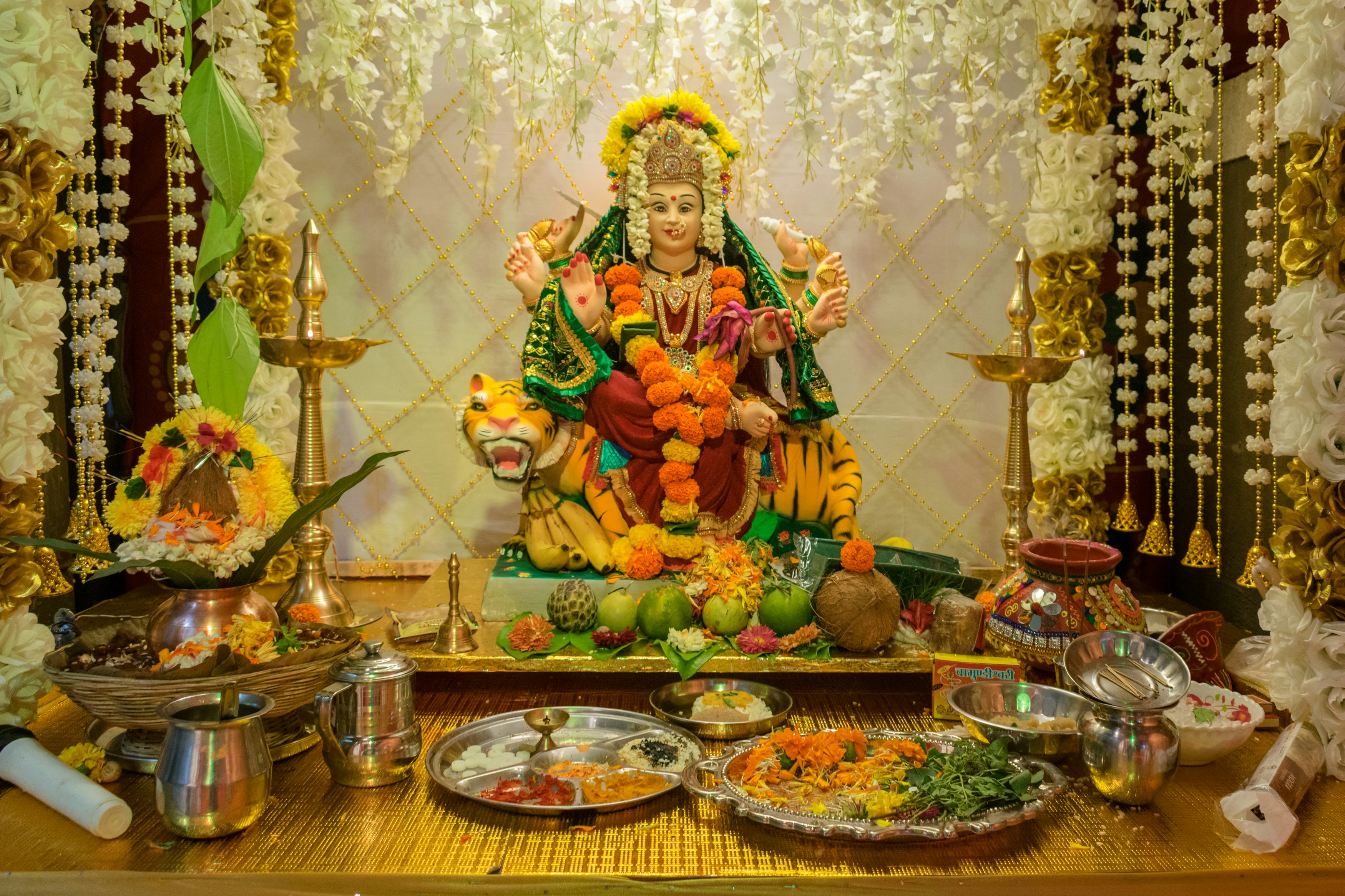 Akshaya Tritiya ritual altar with gold coins, flowers, and oil lamp
